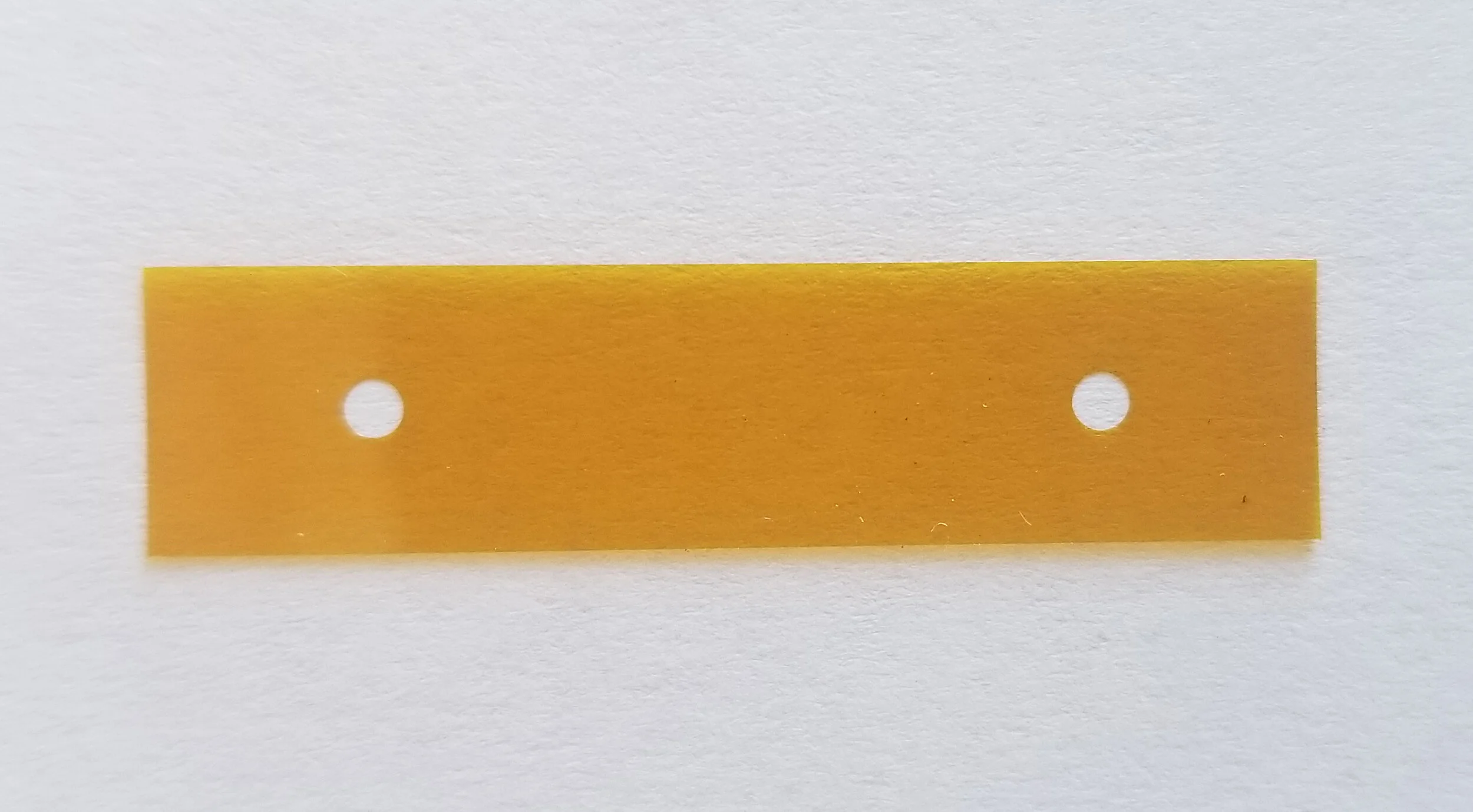An example of die cutting Polyimide Film. This specific part is die cut at 0.001” thick, 40 mm x 10 mm with qty 2 holes at 25 mm.