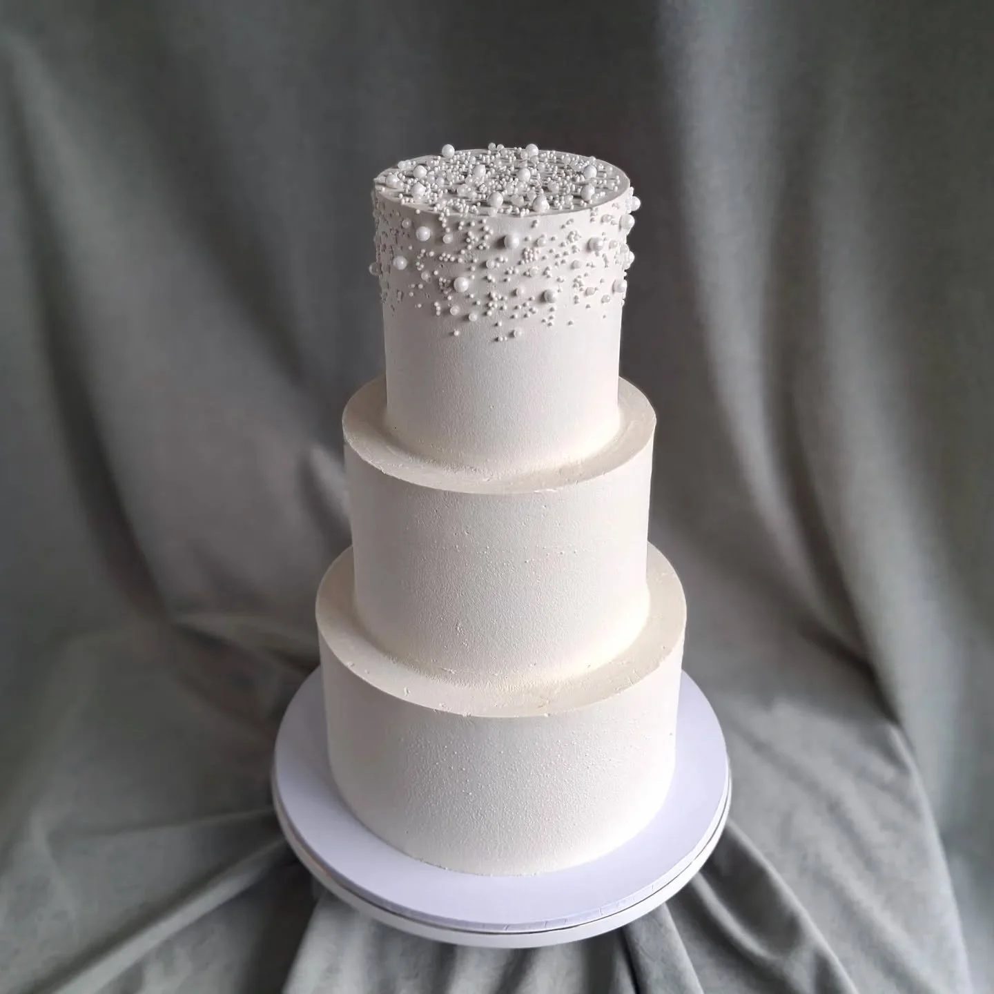 This 3-tiered smooth white wedding cake, topped with sprinkles and pearls was all gluten-free vanilla cake, filled with either lemon or vanilla buttercream 💖💍🥂

#weddingcake #weddingcakestaupo #taupoweddings 
#weddingcakesnz #taupocakes