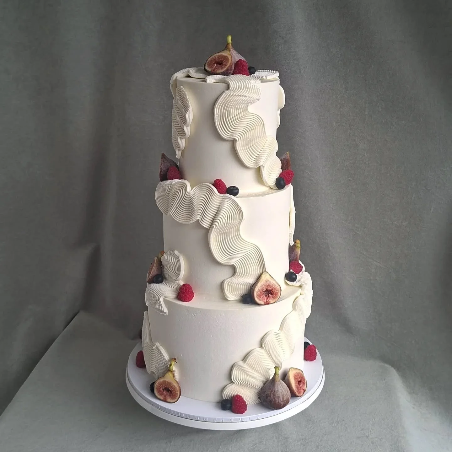 A 3-tiered wedding cake with buttercream squiggles and fresh fruit
