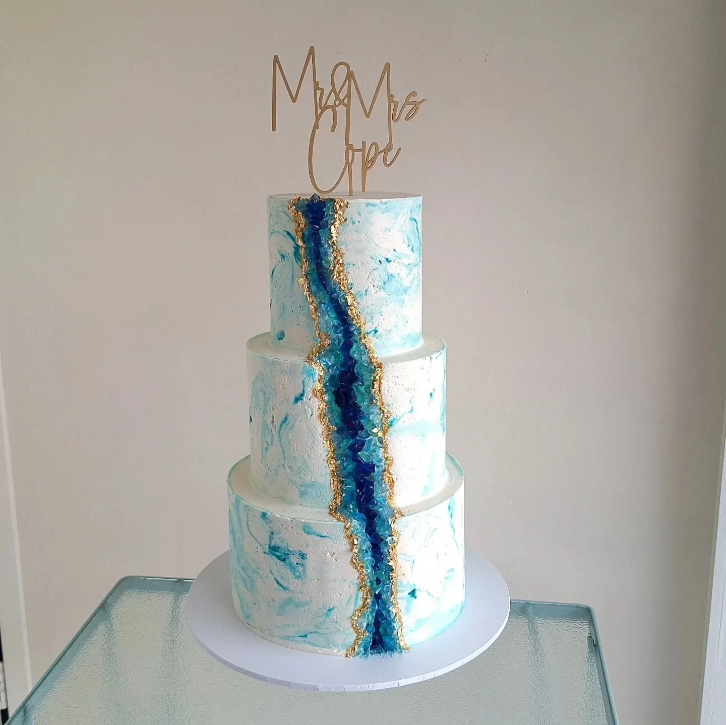 A buttercream marbled 3-tiered wedding cake with a geode river flowing down the front
