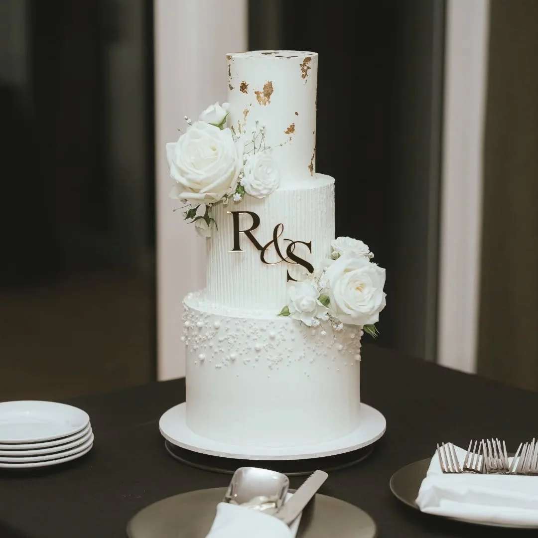 A 3-tiered wedding cake with edible gold leaf, fresh flowers and edible pearls