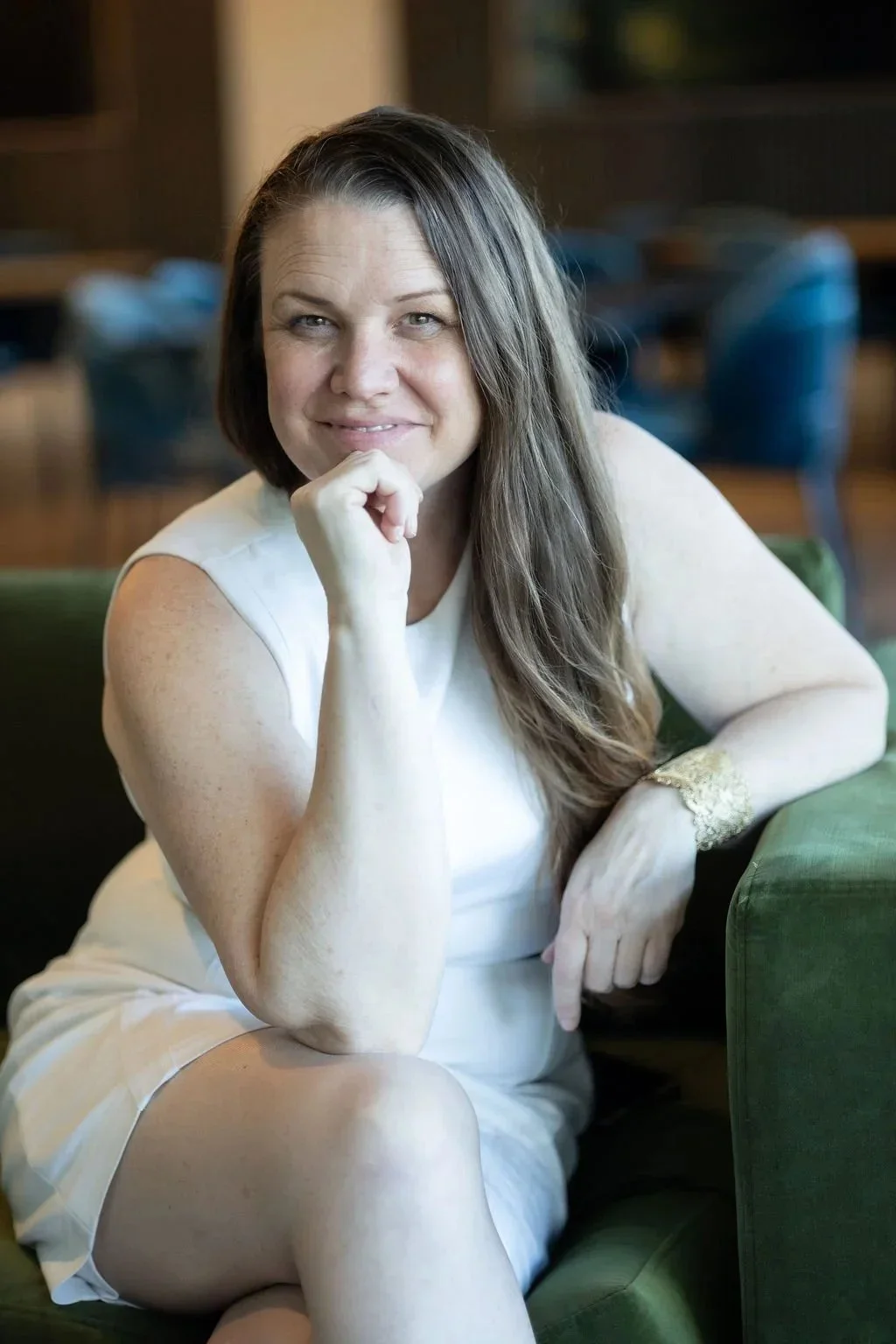 Meghan Simington in a white dress on a green chair