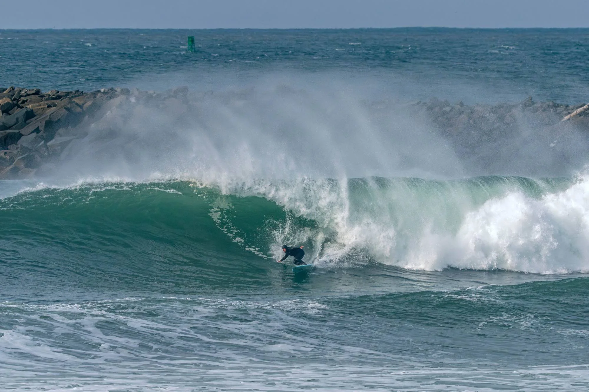 Surfer catching a wave near jetty