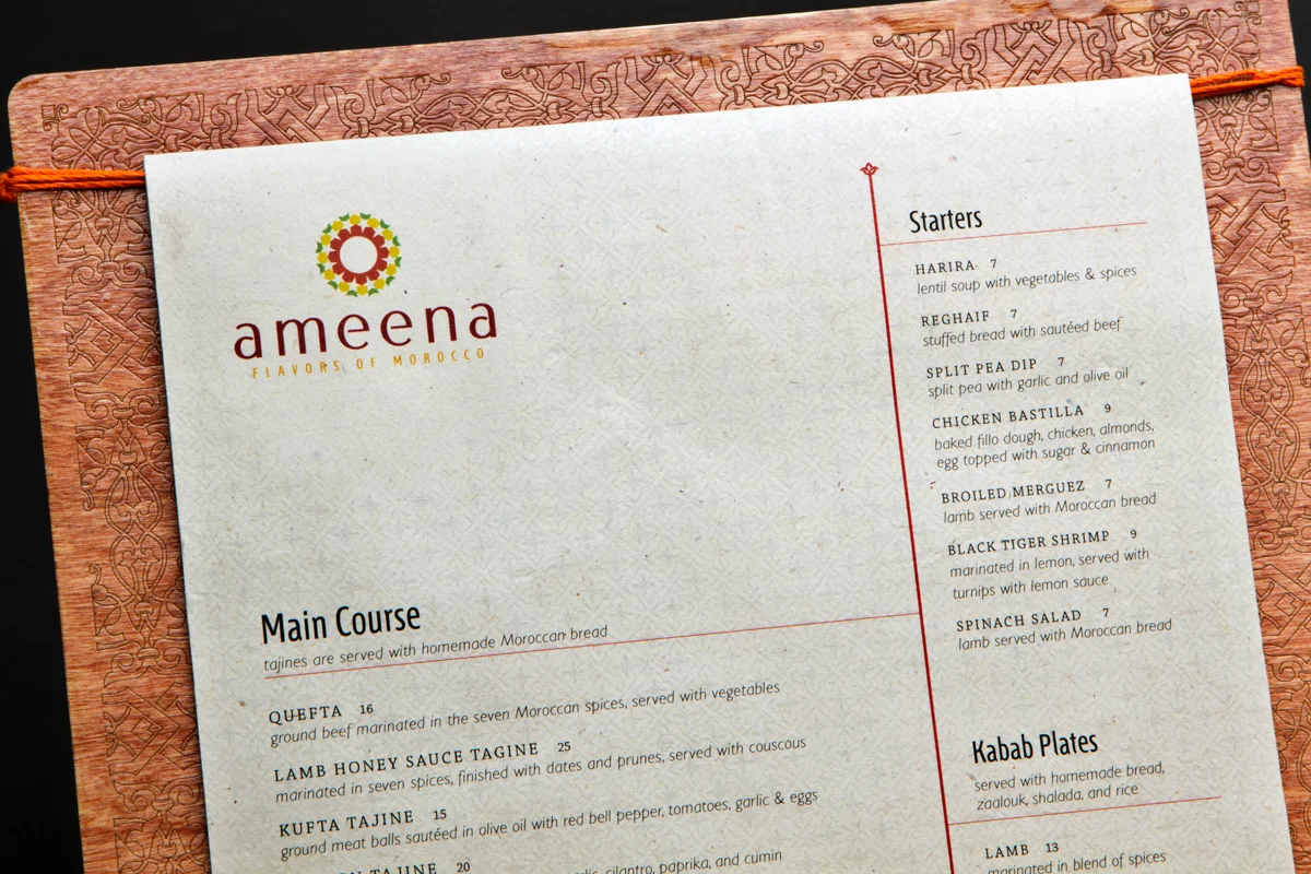 Close-up of dinner menu. Details on paper and wood carving around the border can be seen.