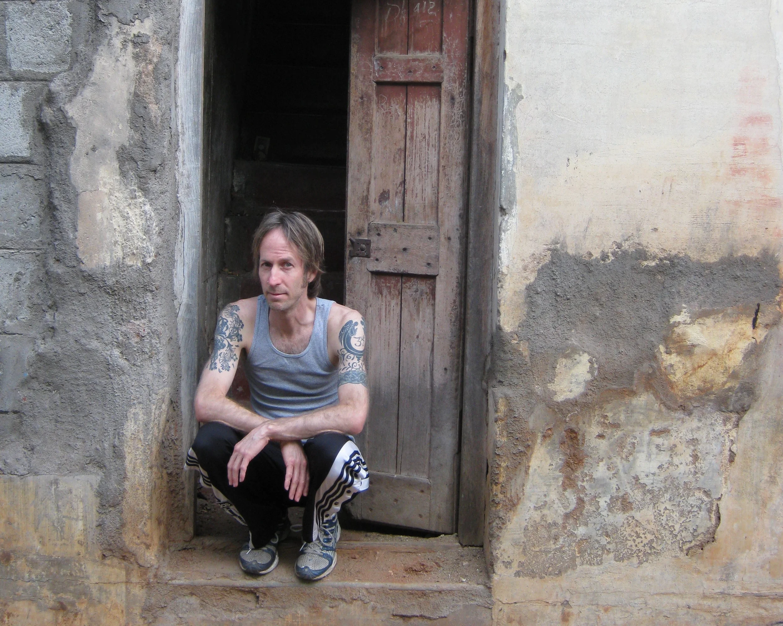 Los Angeles yoga teacher Daniel Overberger squatting in the doorway of an old building in Mysore, India.jpg
