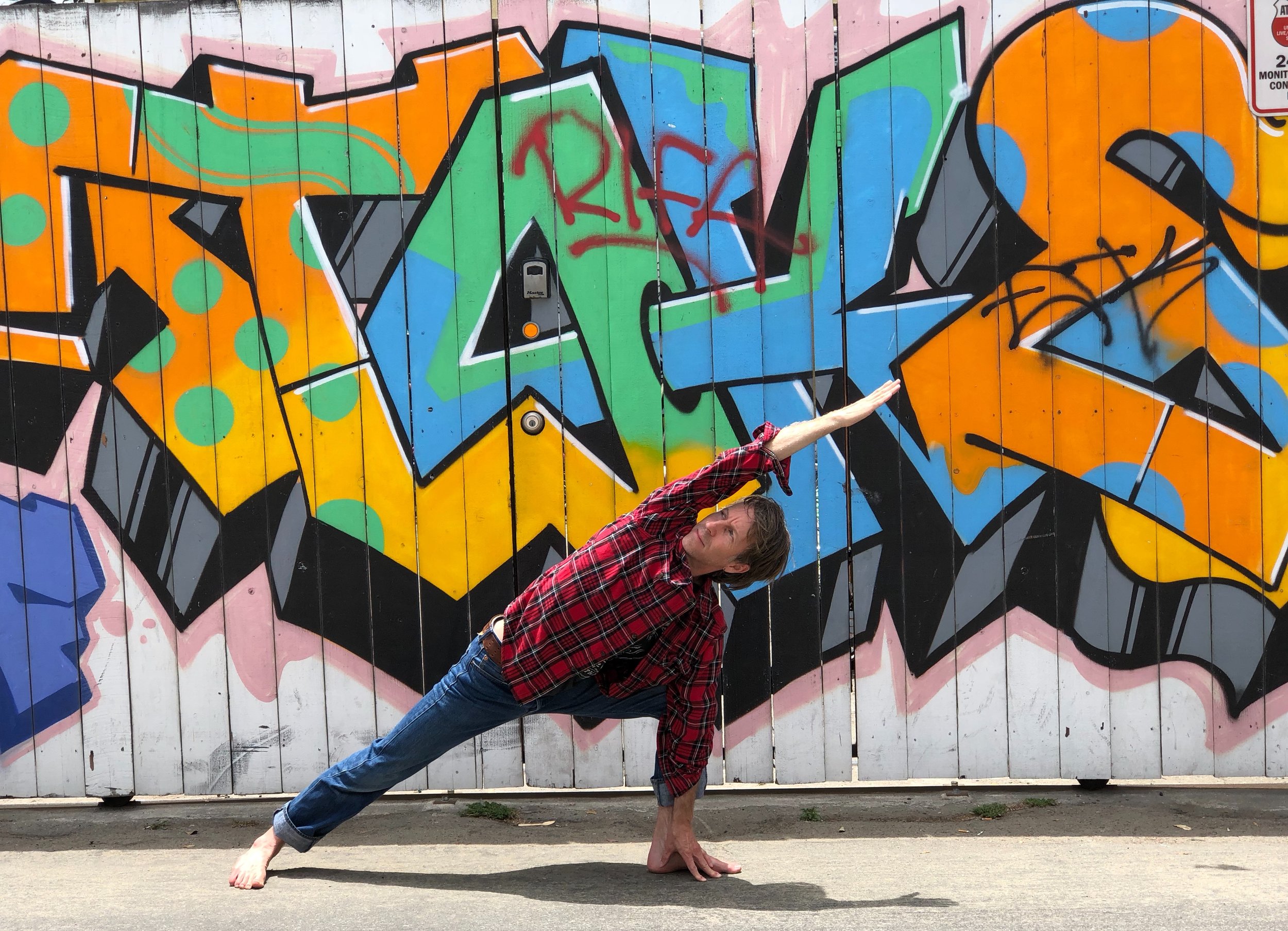 Los Angeles yoga teacher Daniel Overberger performing extended side angle pose in front of a wall of graffiti.jpg