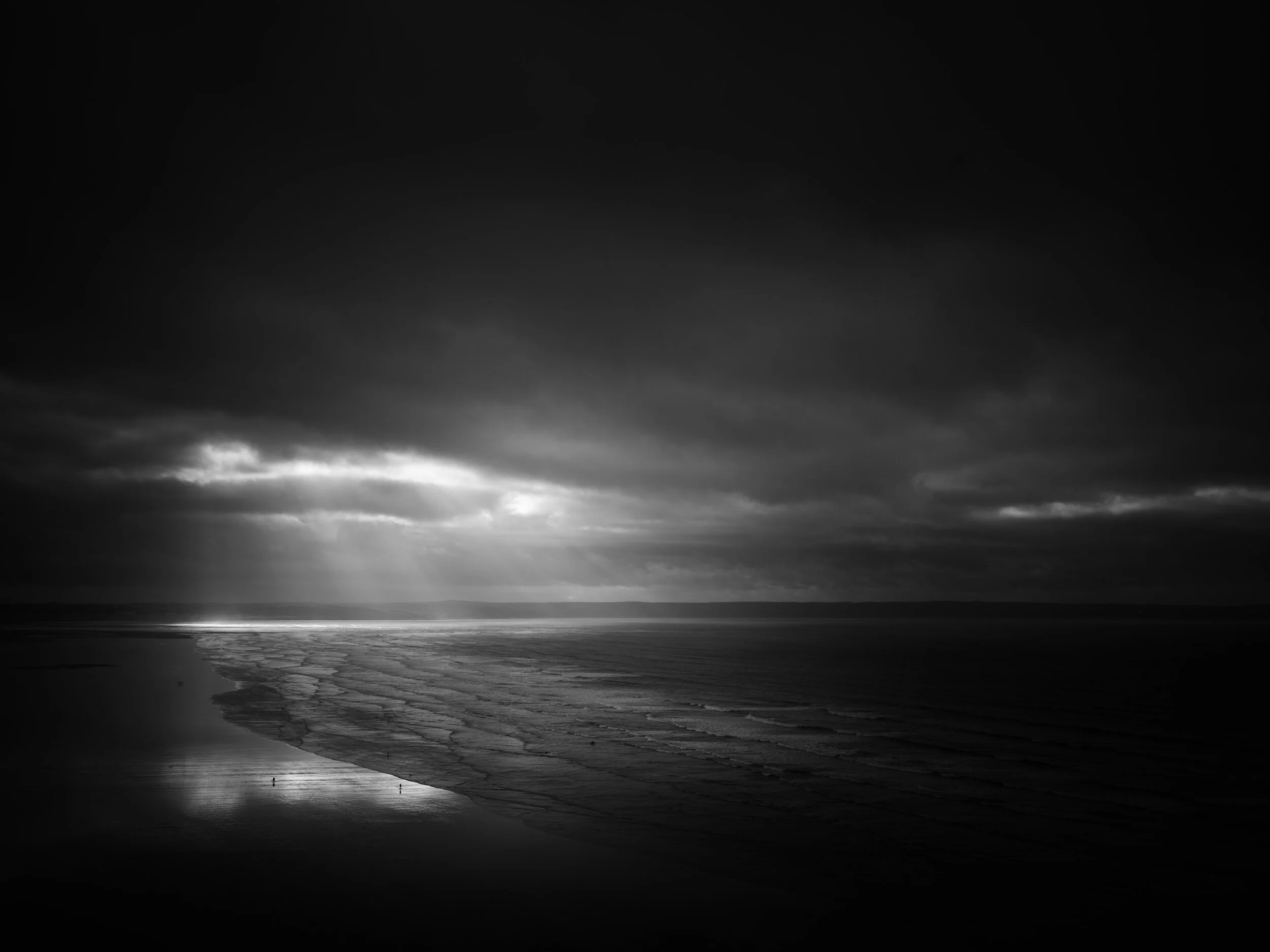 black and white dramatic light breaks through clouds above saunton sands beach, Devon UK. Photographed by Freddie Ardley
