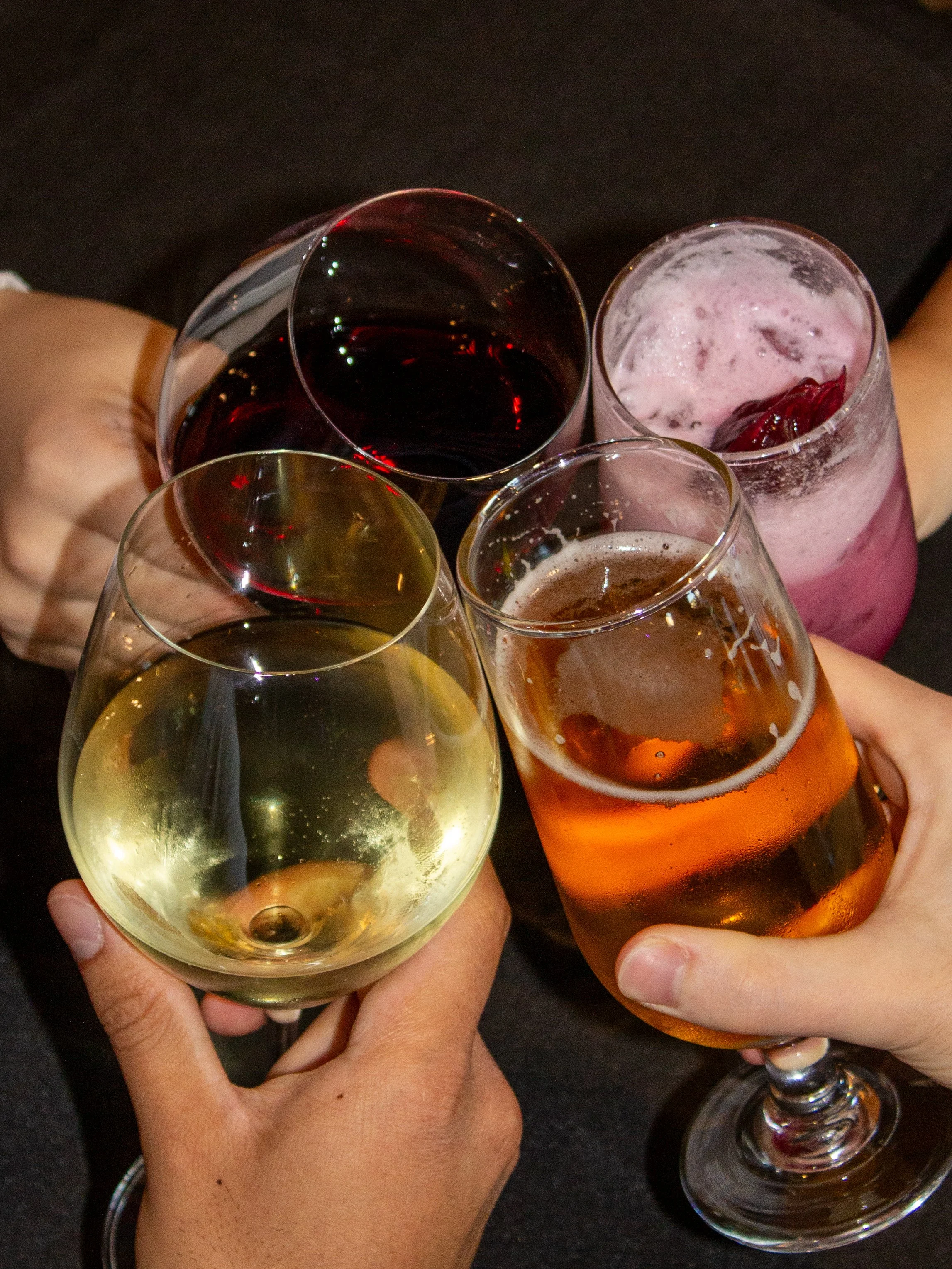 Person pouring red wine into a wine glass.