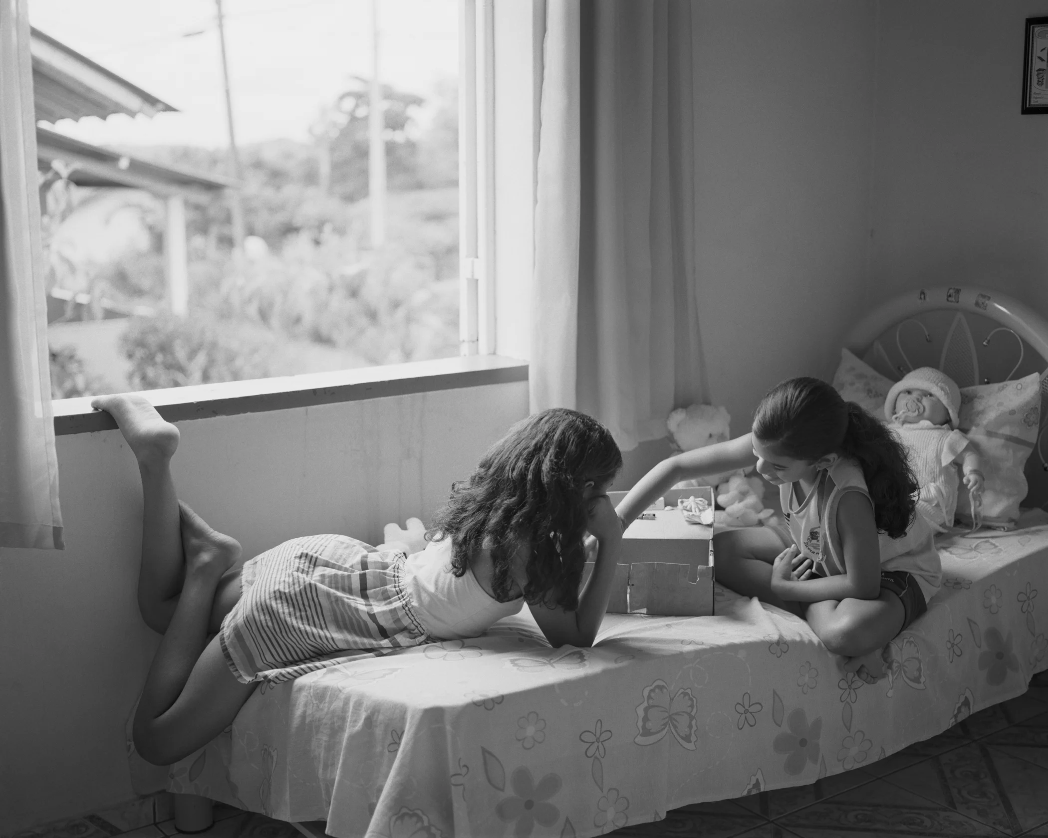 Ivna and Lara playing house inside the Farias family home at company housing complex Vila 4, April, 2014, Michelin Rubber Plantation, Bahia, Brazil. 2014/2018