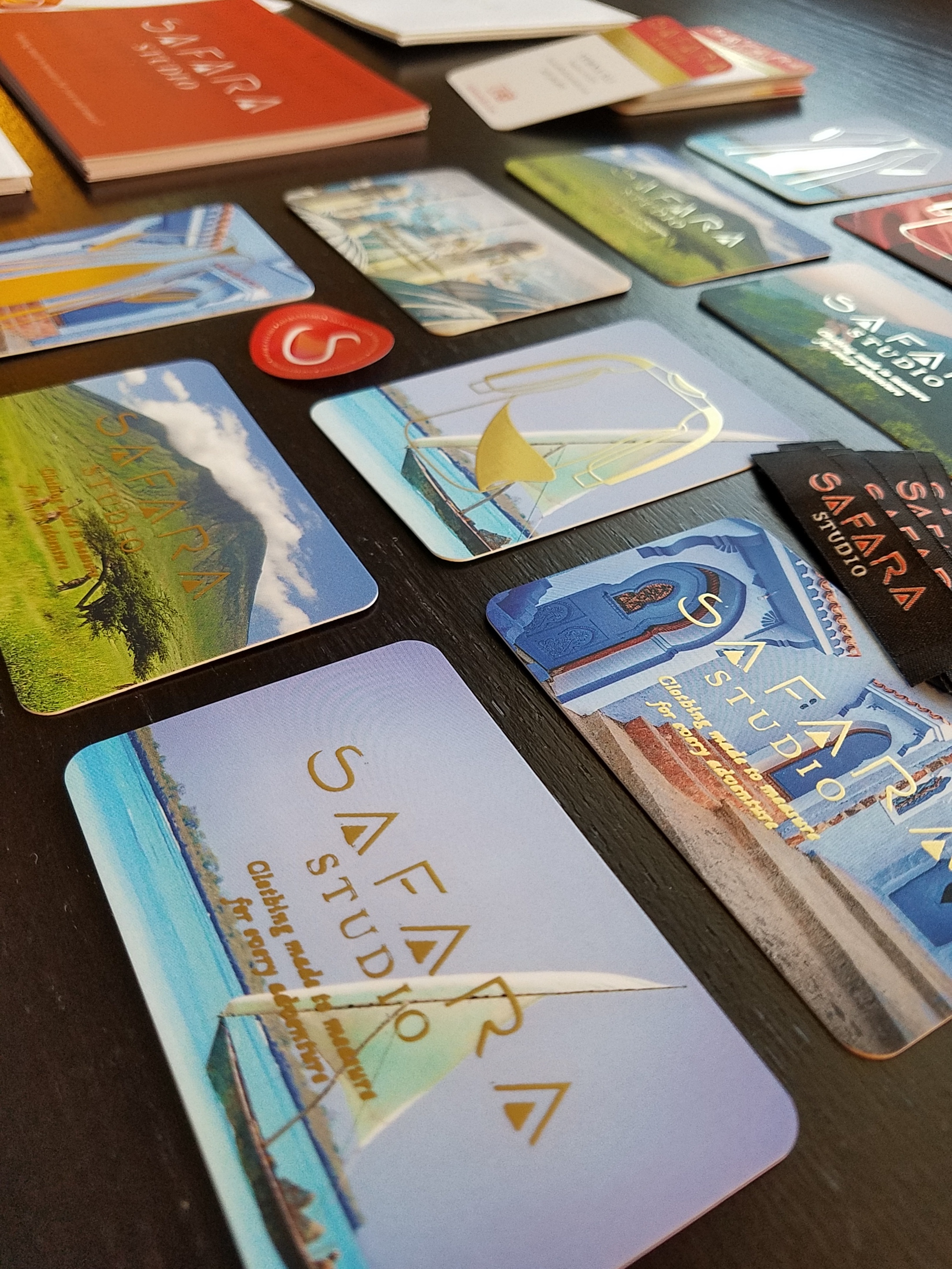 Travel brochures and cards, including a TRAVEL themed brochure, laid out on a table with a dark surface.