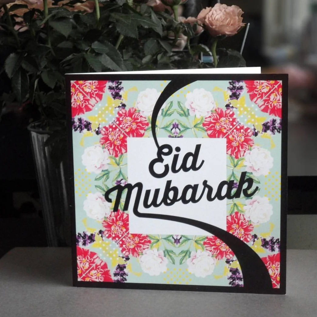 A colorful Eid Mubarak greeting card with floral patterns and a black lettering that says 'Eid Mubarak'.