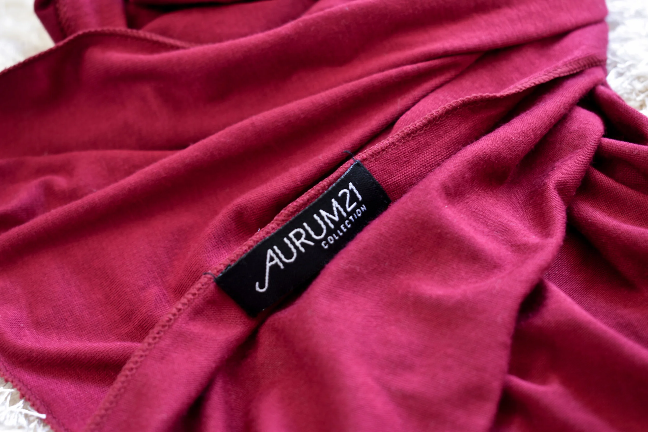 Close-up of pink fabric with a black tag that reads 'AURUM21 COLLECTION' on it.