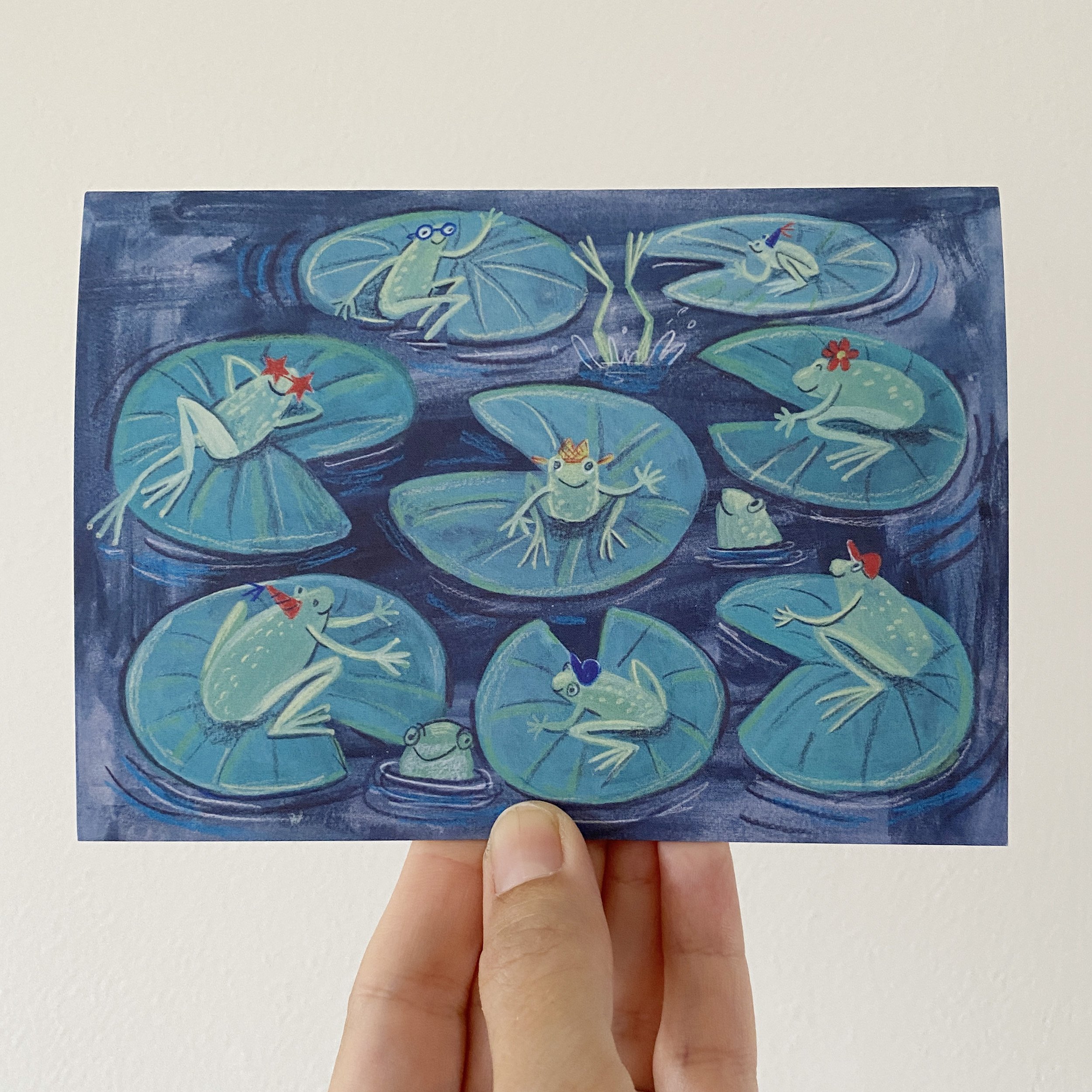 Frogs wearing hats having a pool party greetings card