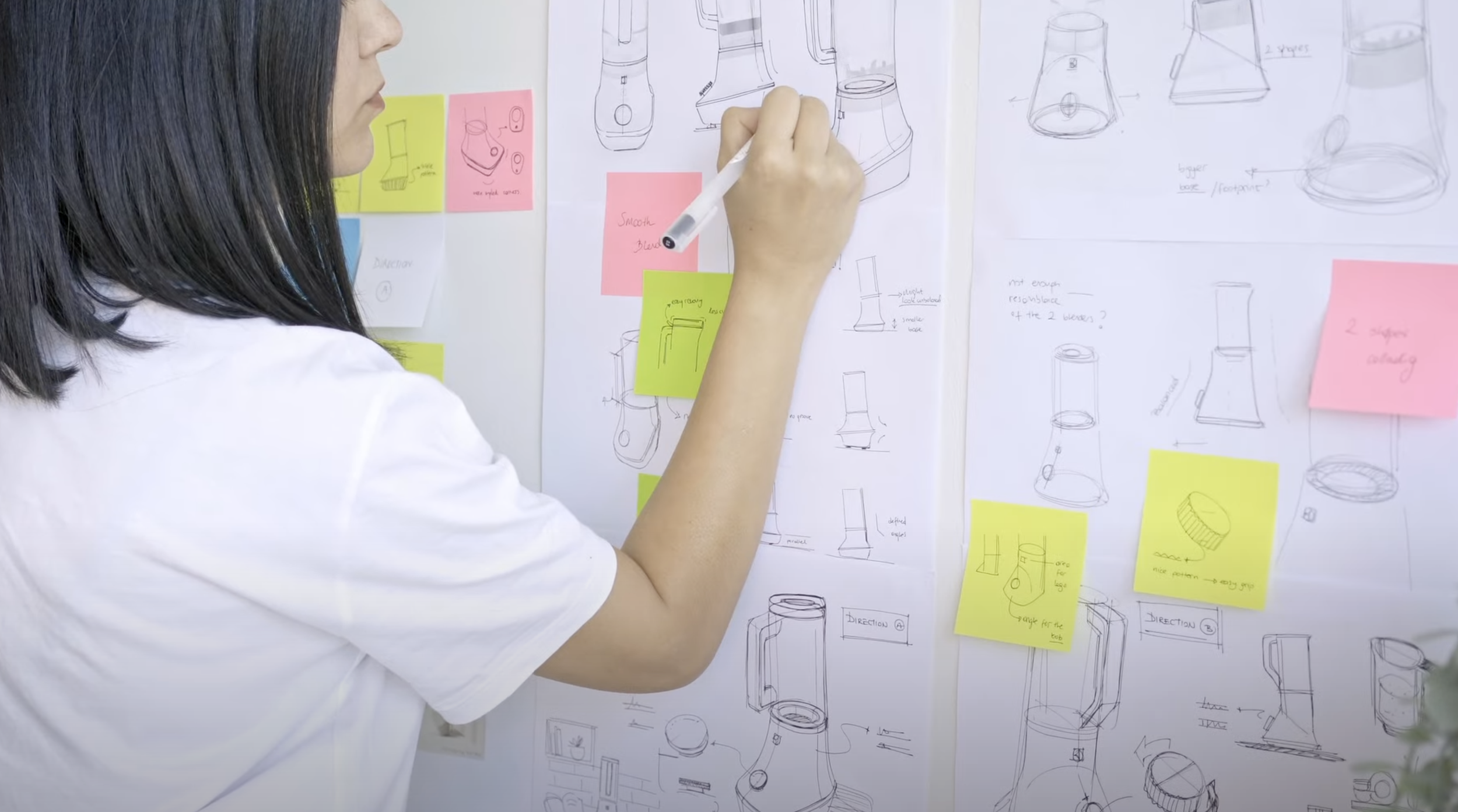 Ideation wall with sketches and product design concepts and colored sticky notes.