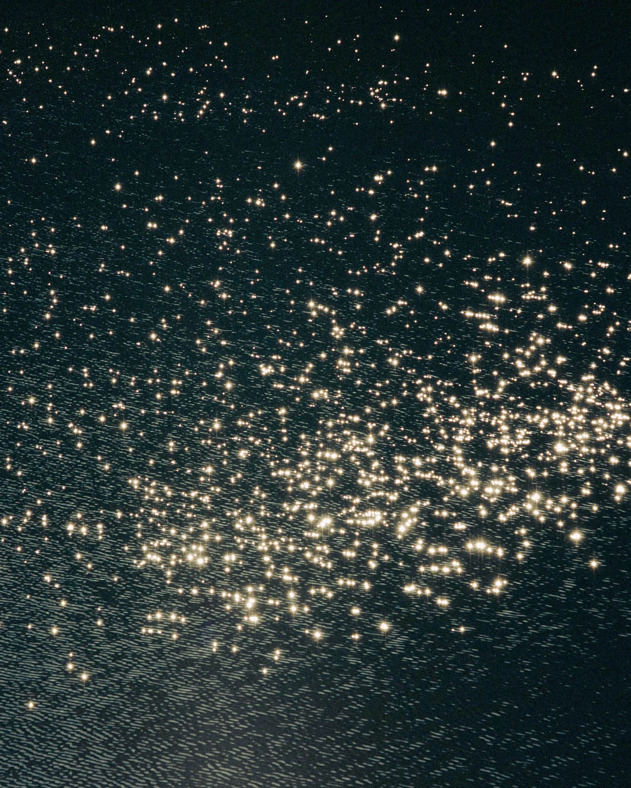 A starry night sky with numerous bright stars scattered across a dark background, appearing as a cosmic scene.