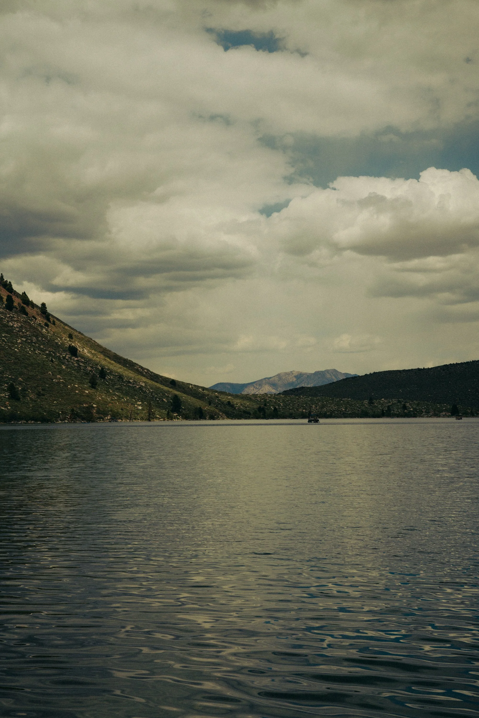 A large body of water surrounded by mountains under a partly cloudy sky.