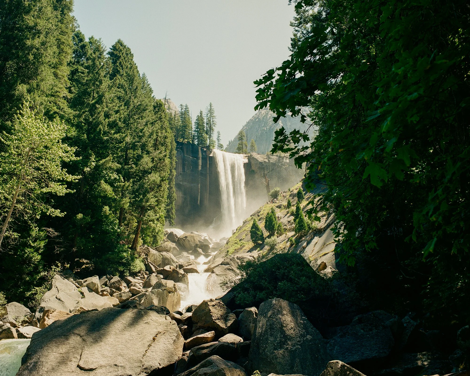 A waterfall flowing down a cliff surrounded by lush green trees and rocks.