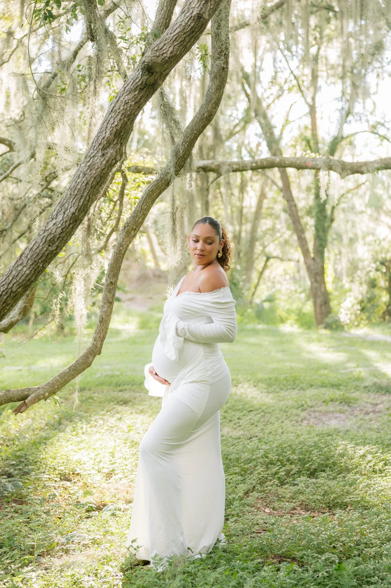 An expecting mother holding her belly, walking on the beach for her Tampa, FL maternity session.