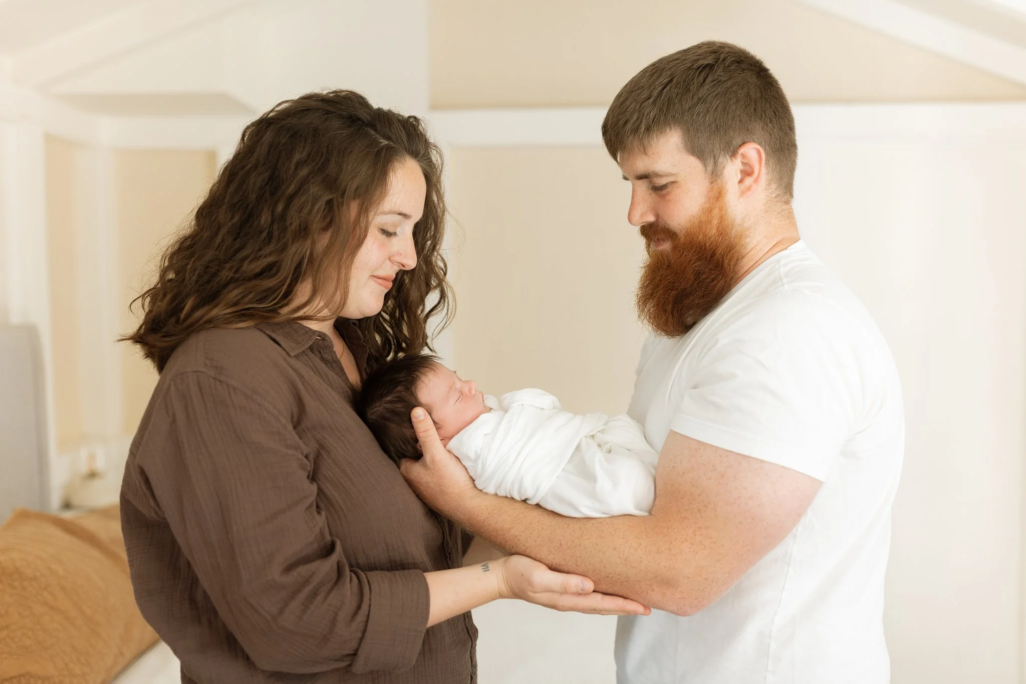 Mom and dad holding their newborn baby in their home for an at-home newborn session in Tampa, FL.