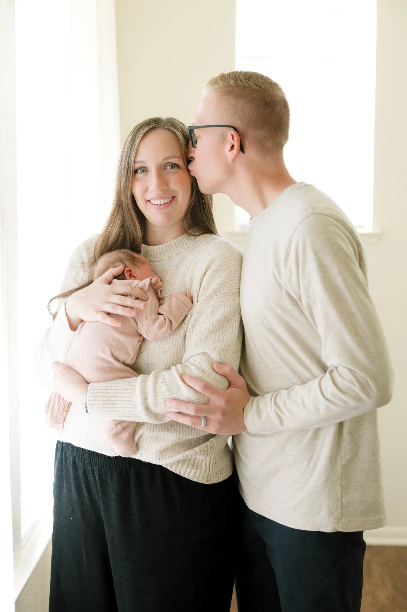 Mom and dad holding newborn baby in their home during a Tampa, FL at-home newborn photo session.