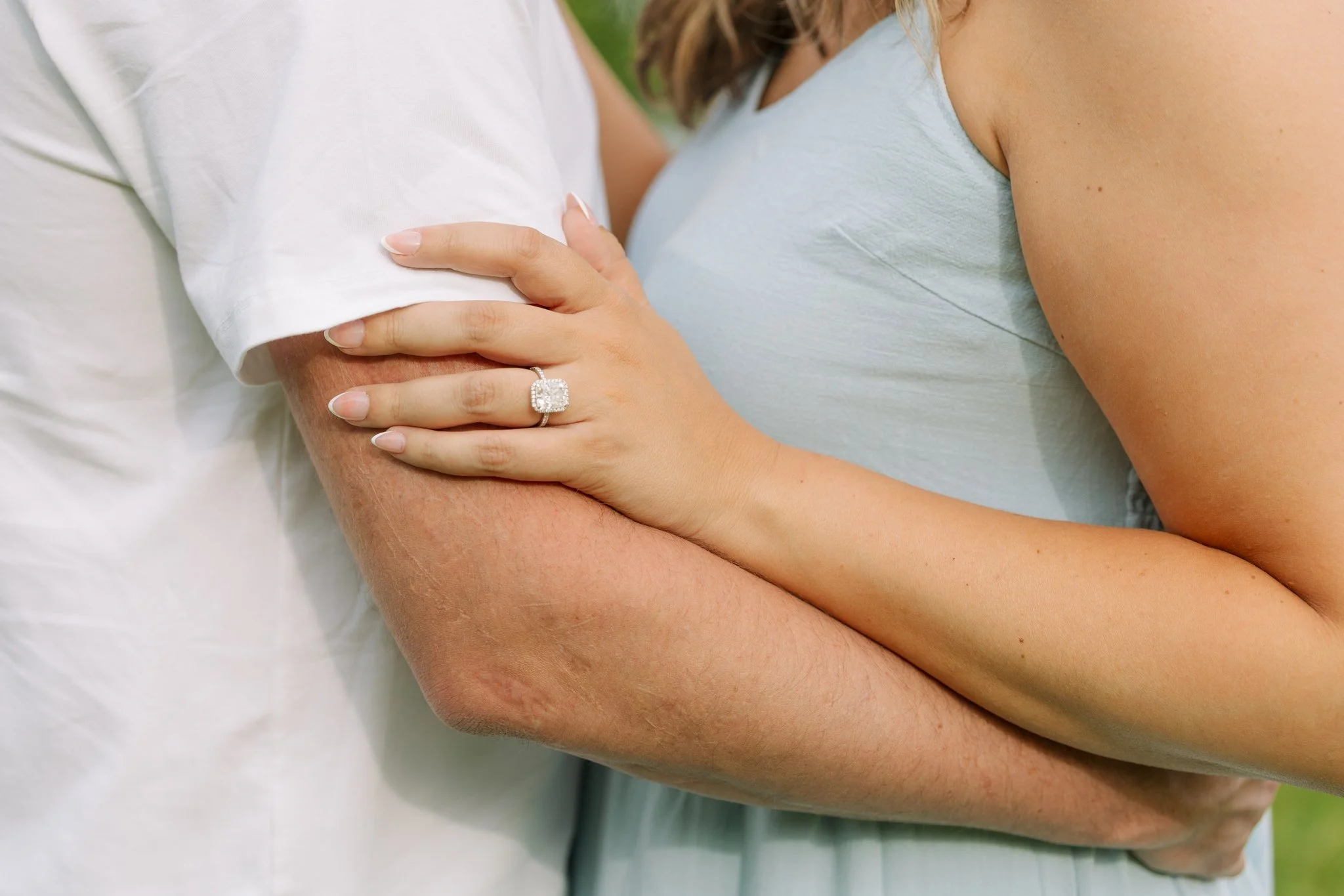 A close up photo of a couple hugging, showing the ring, for a Tampa, FL engagement session