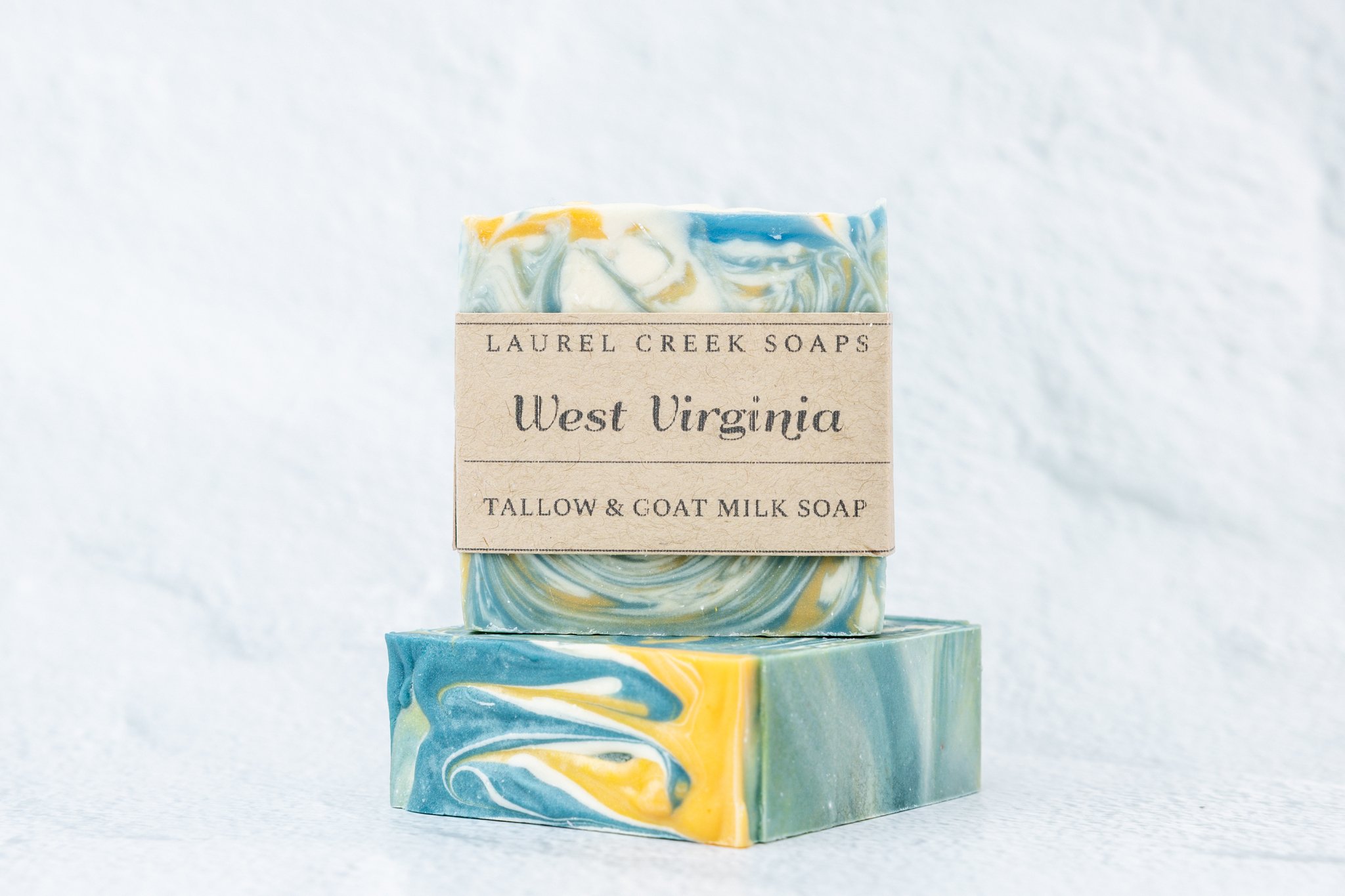 West Virginia tallow and goat milk soap with blue and gold swirls on white marble