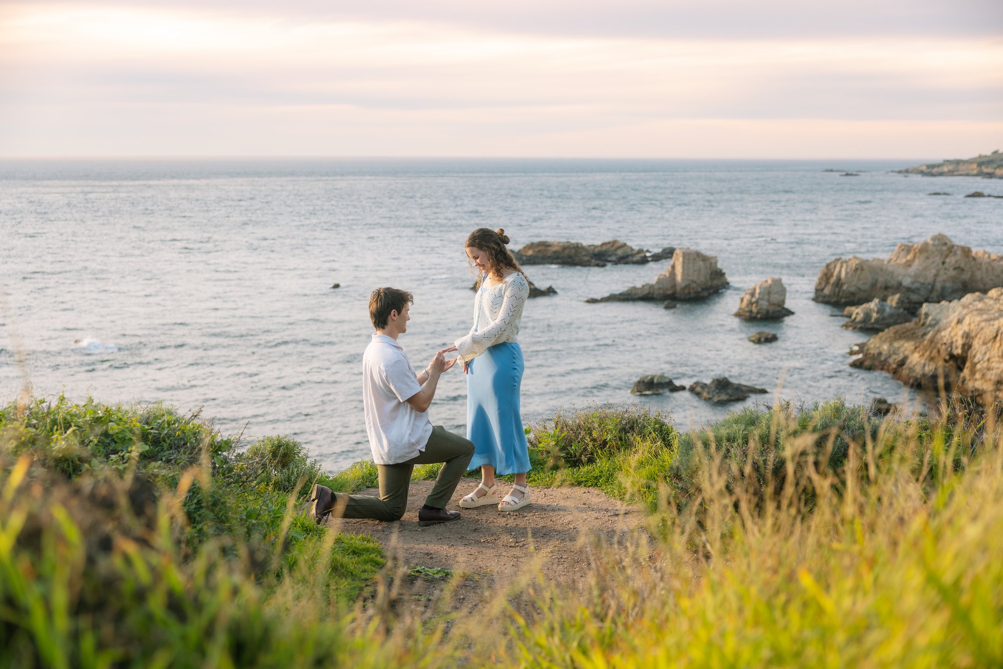 Photo of a couple overlooking the water while the male is down on a knee proposing to his fiancé during a Tampa, FL surprise proposal.