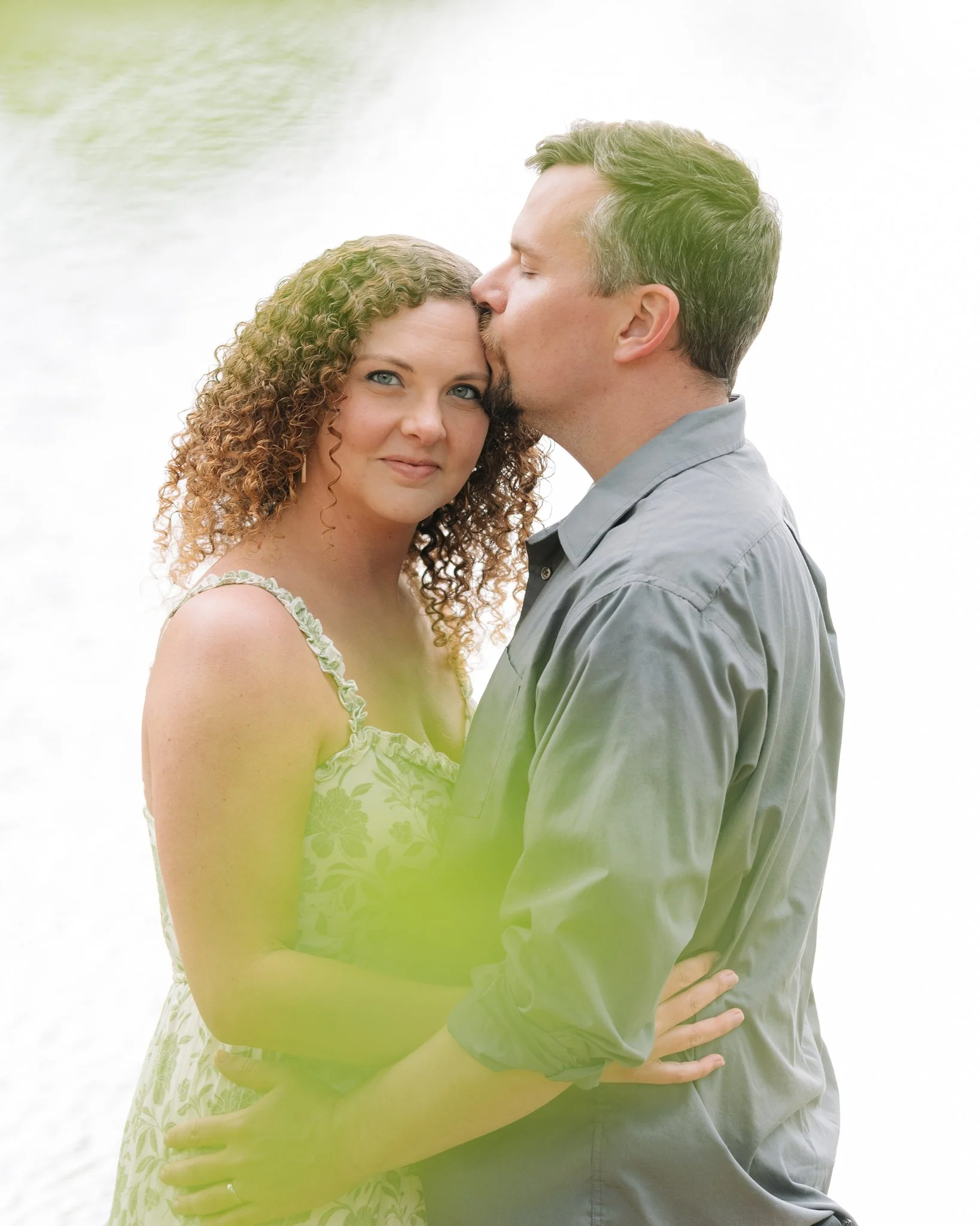 A couple embracing as the male kisses the woman's temple, posing for a couples photo in Tampa, FL.