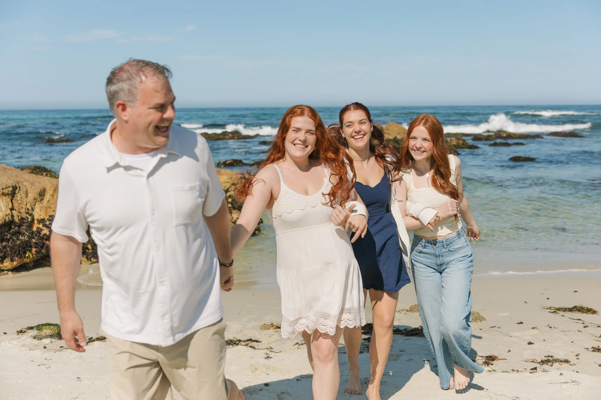 Family smiling and running on the beach during a Tampa Bay family photo session.