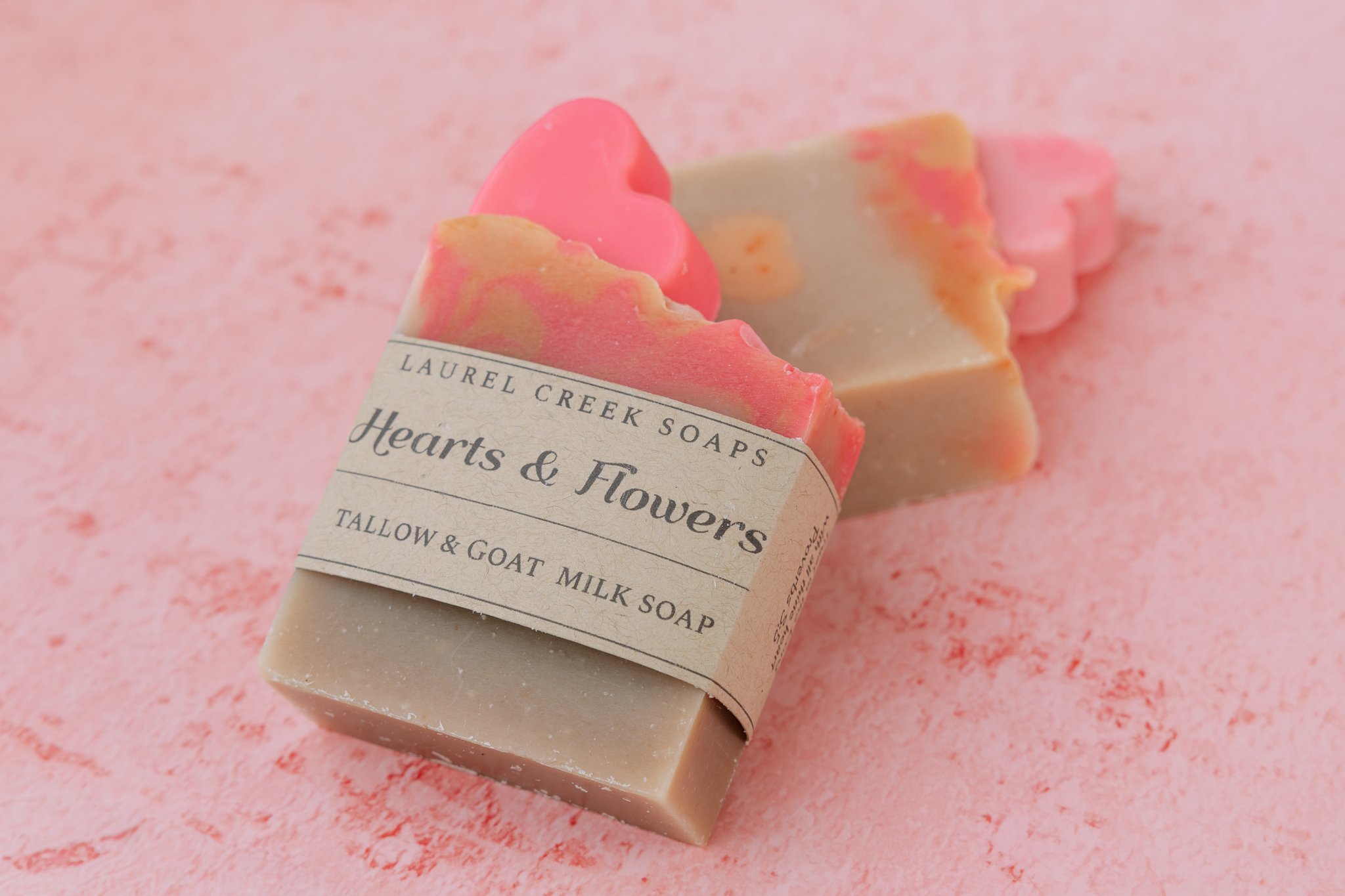 Hearts and Flowers tallow and goat milk soap topped with pink soap hearts on a pink background