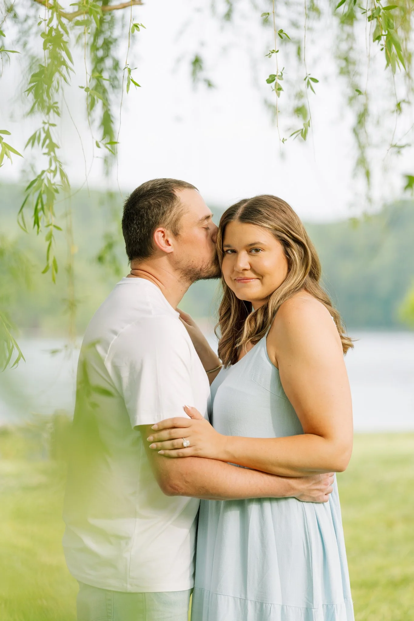 A couple standing in a weeping willow, posing for an engagement photo in Tampa, FL.