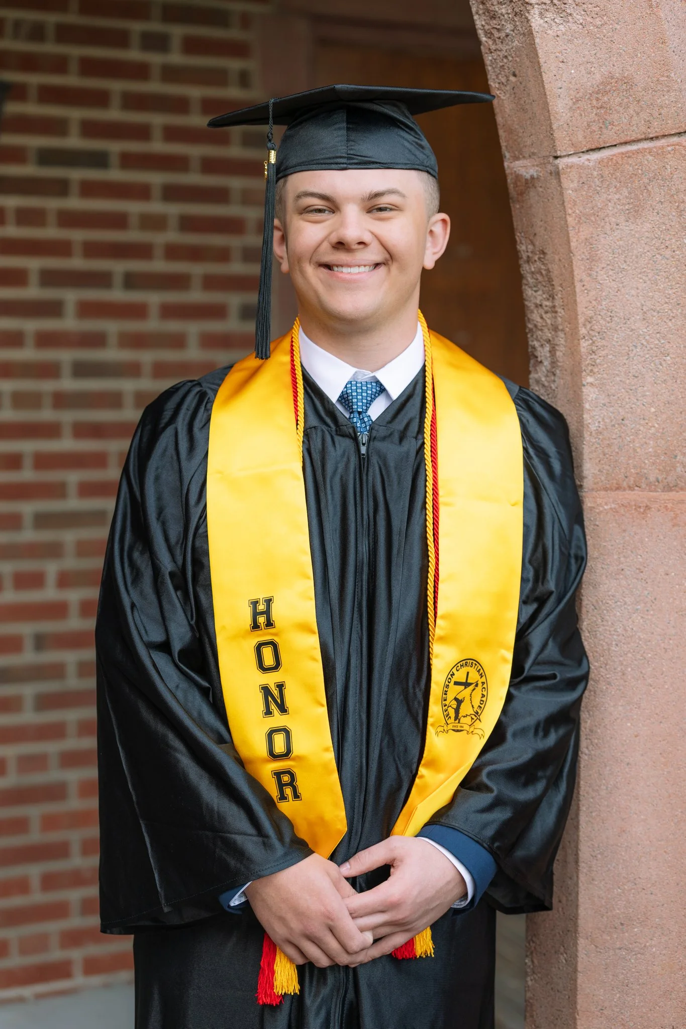 A senior graduate in his cap and gown posing for a senior photo session in Tampa, FL.