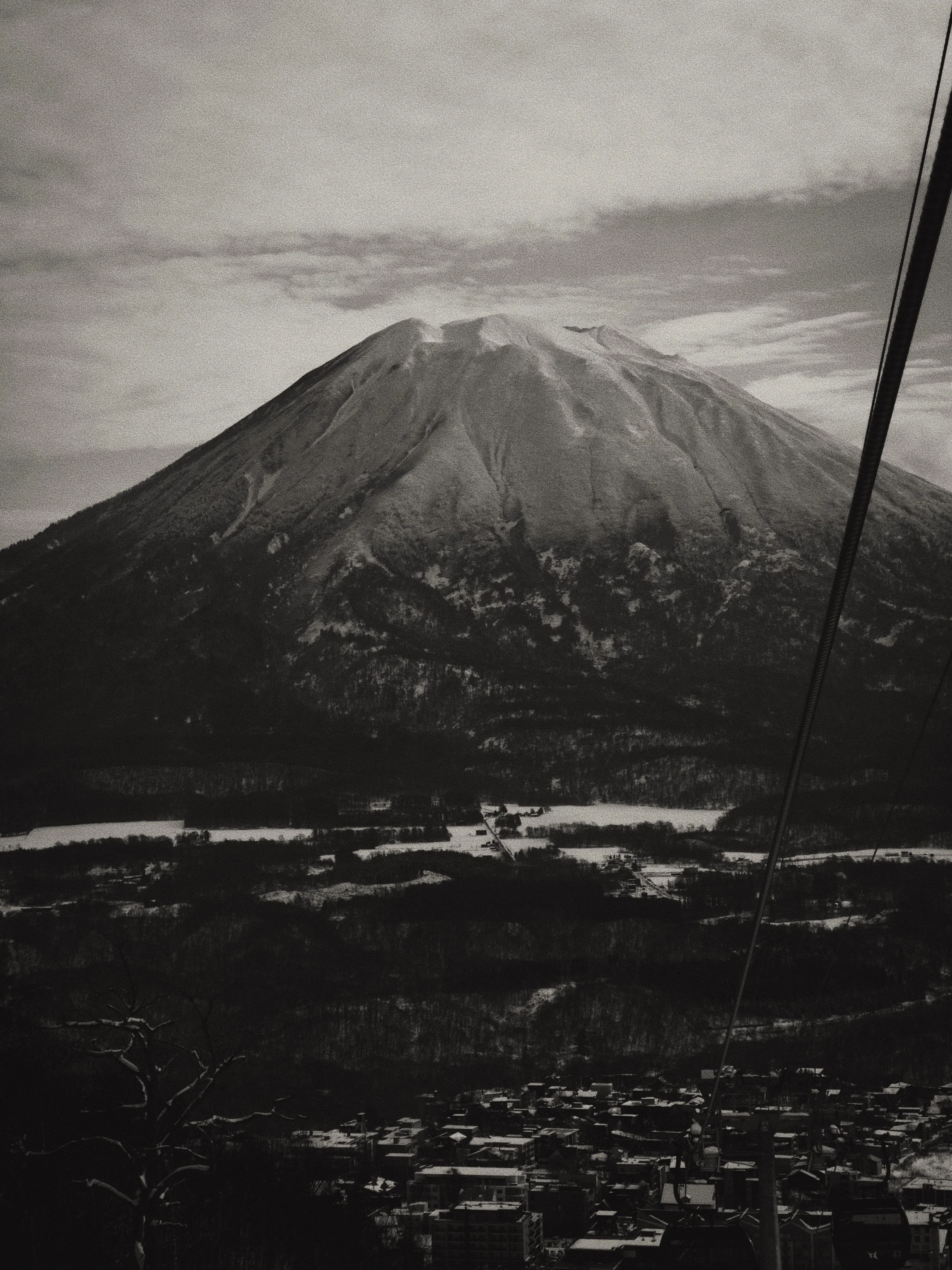 Black and white photo taken from the Ace Gondola in Hirafu, Niseko of Mount Yotei towering over with plenty of snow ontop