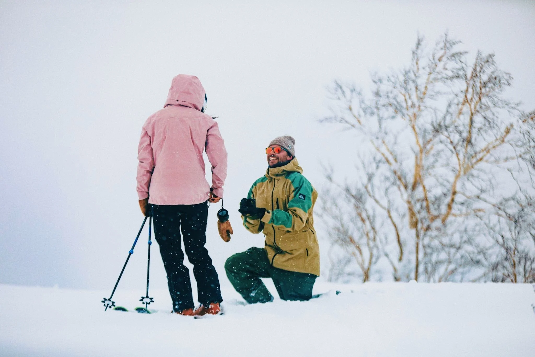 Couple celebrating a marriage proposal on a snowy mountain in Kiroro, Japan.