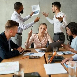 Gruppe von Büroangestellten diskutiert angespannt über Dokumente, während eine Frau am Tisch gestresst wirkt. Symbolbild für Change Fatique in Unternehmen