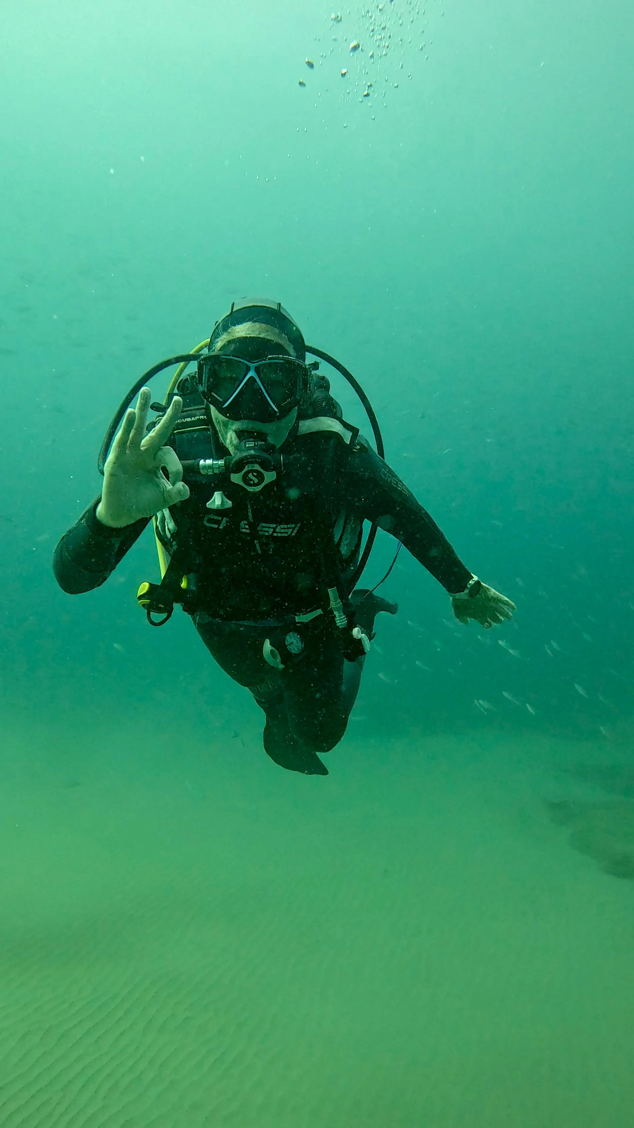 Scuba diver underwater making an OK hand sign.