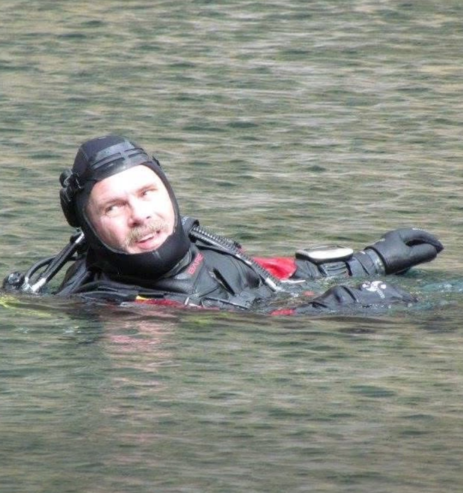 A man in scuba diving gear floating in a body of water.