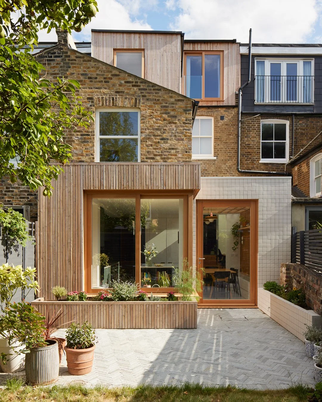 TIMBER &amp; TILE

The seating nook is wrapped in Scottish larch battens, while the dining area is finished in white tiles, forming two distinct yet complementary volumes. Together, these materials echo the tones of the existing buff brickwork and wh