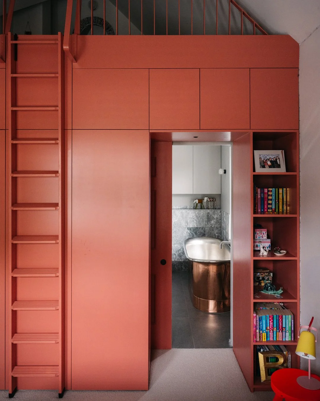 SUBURBAN HOUSE

The new first floor rear extension was designed with a vast and spacious vaulted ceiling. What could have been a simple bedroom became far more, with a mezzanine space sitting atop a dramatic piece of coral coloured joinery. This is n