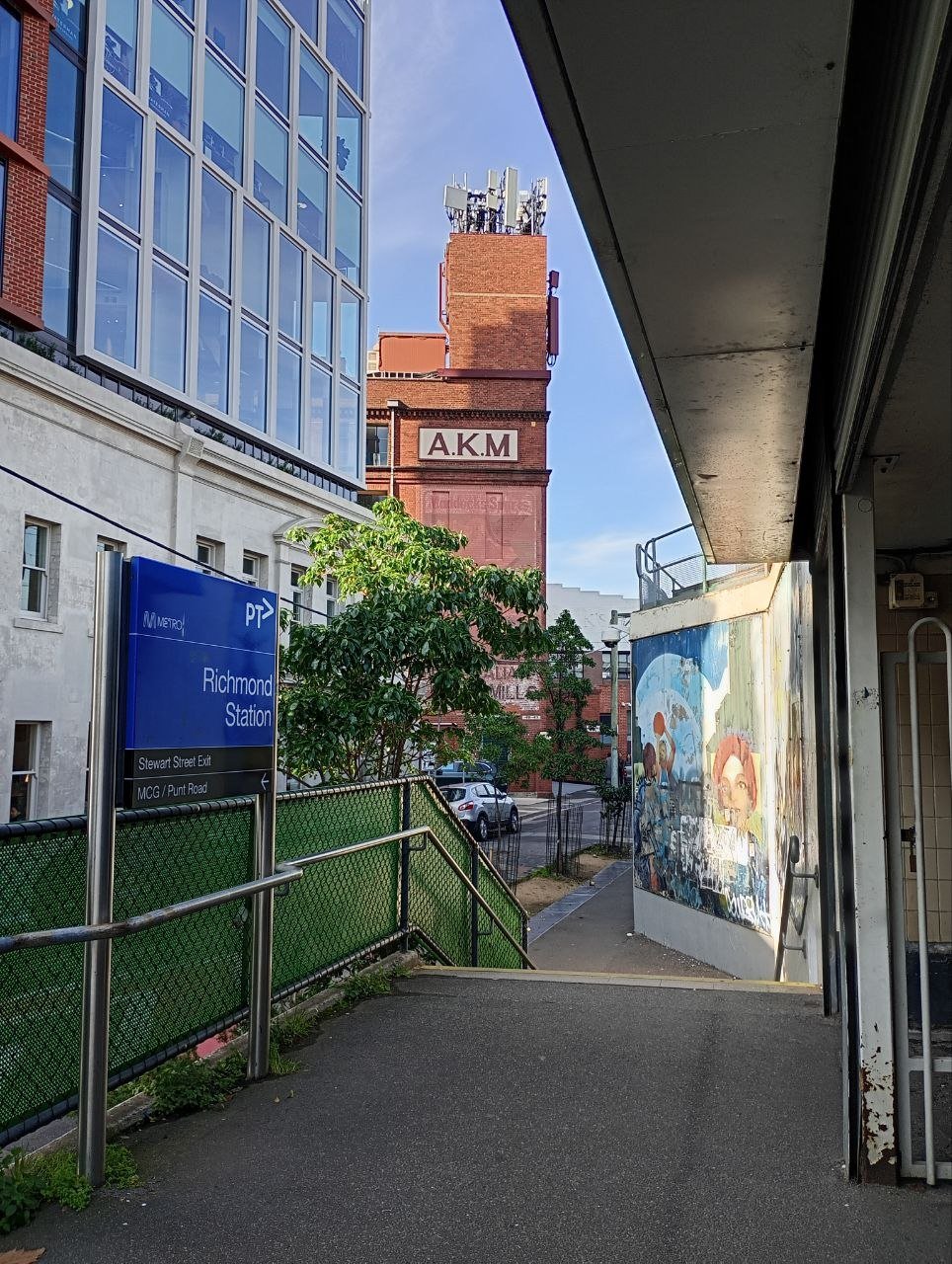 Entrance to Richmond Station with a blue metro sign, approaching stairs, and a mural on the wall outside.