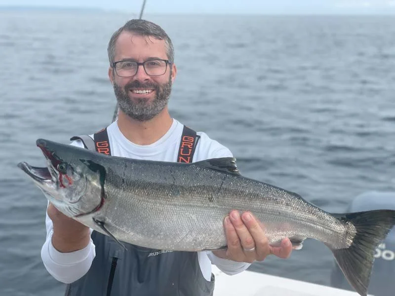 A man holding  a Puget Sound Coho or Silver Salmon on wind knot guides