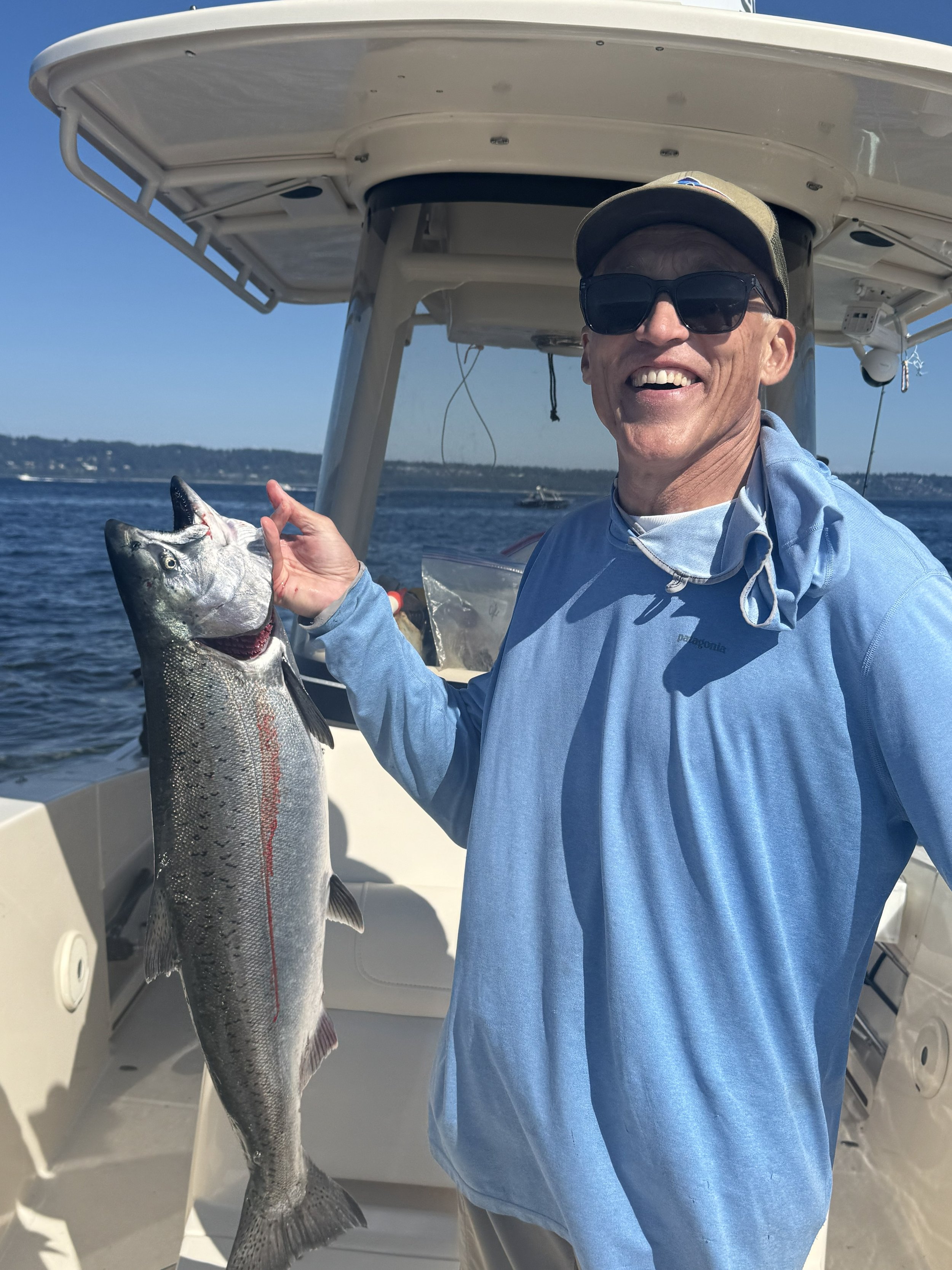A happy angler presenting an Chinook salmon on wind knot guides seattle salmon charter