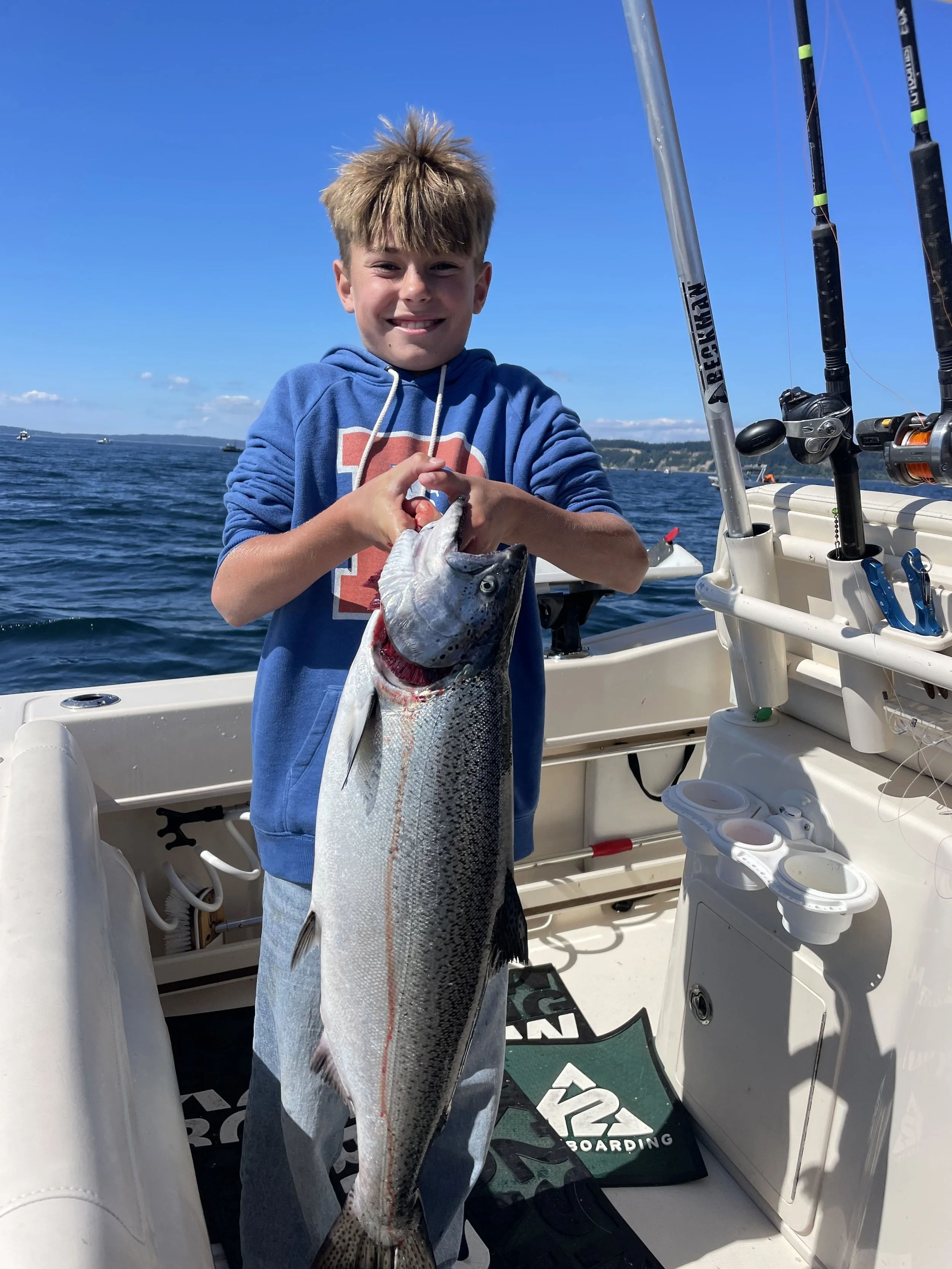 A young boy proudly presents a hatchery Chinook salmon  guided by Captain Dave of Wind Knot Guides and Seattle Salmon Charters