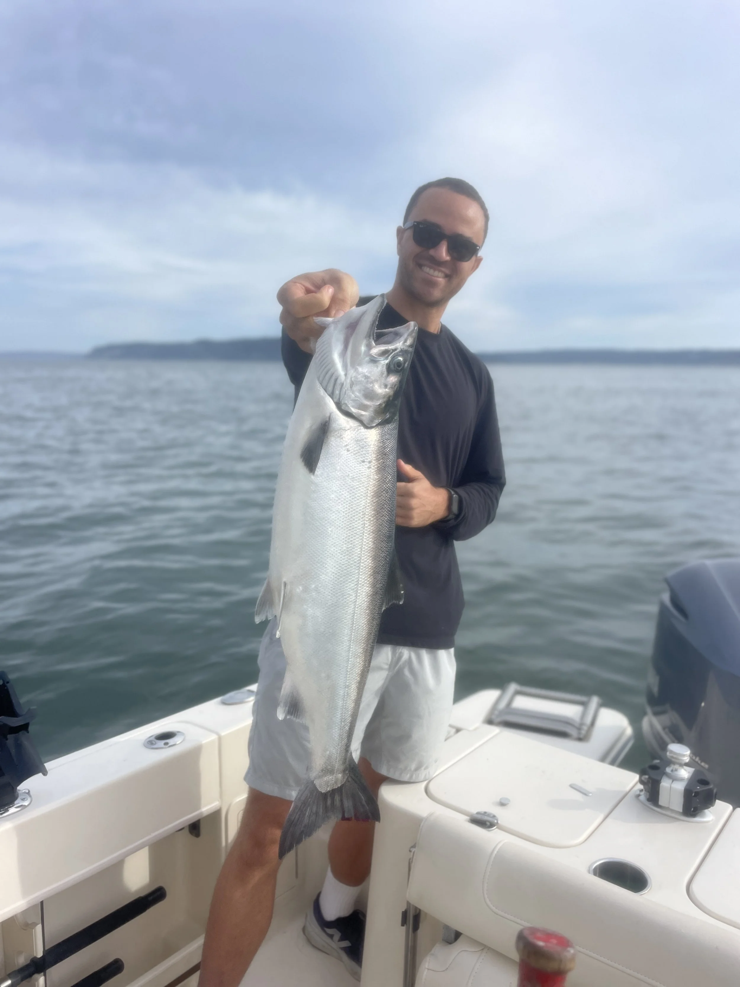 A man hold his freshly caught coho salmon while fishing with Wind Knot guides on the morning silver salmon charter