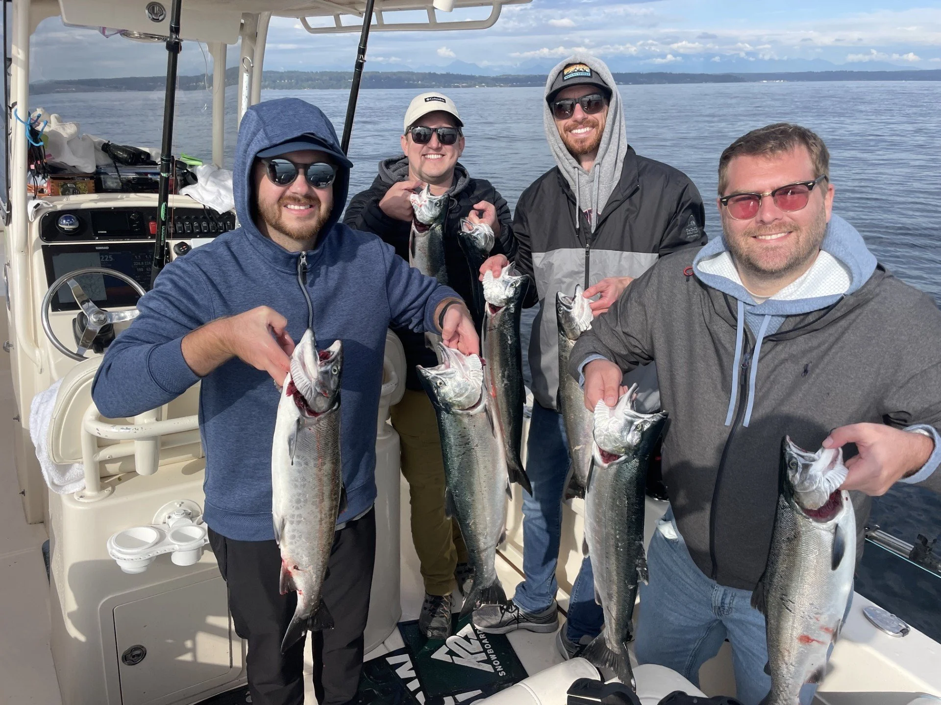 A group of four anglers posing with freshly caught Coho Salmon on the Wind Knot Guides Morning Salmon Charter