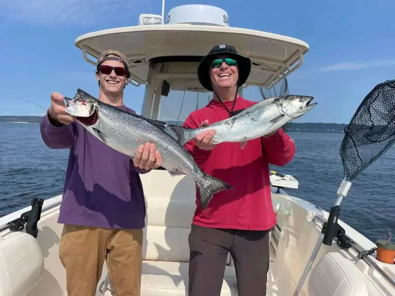 a man and son holding freshly caught salmon on a seattle salmon fishing charter