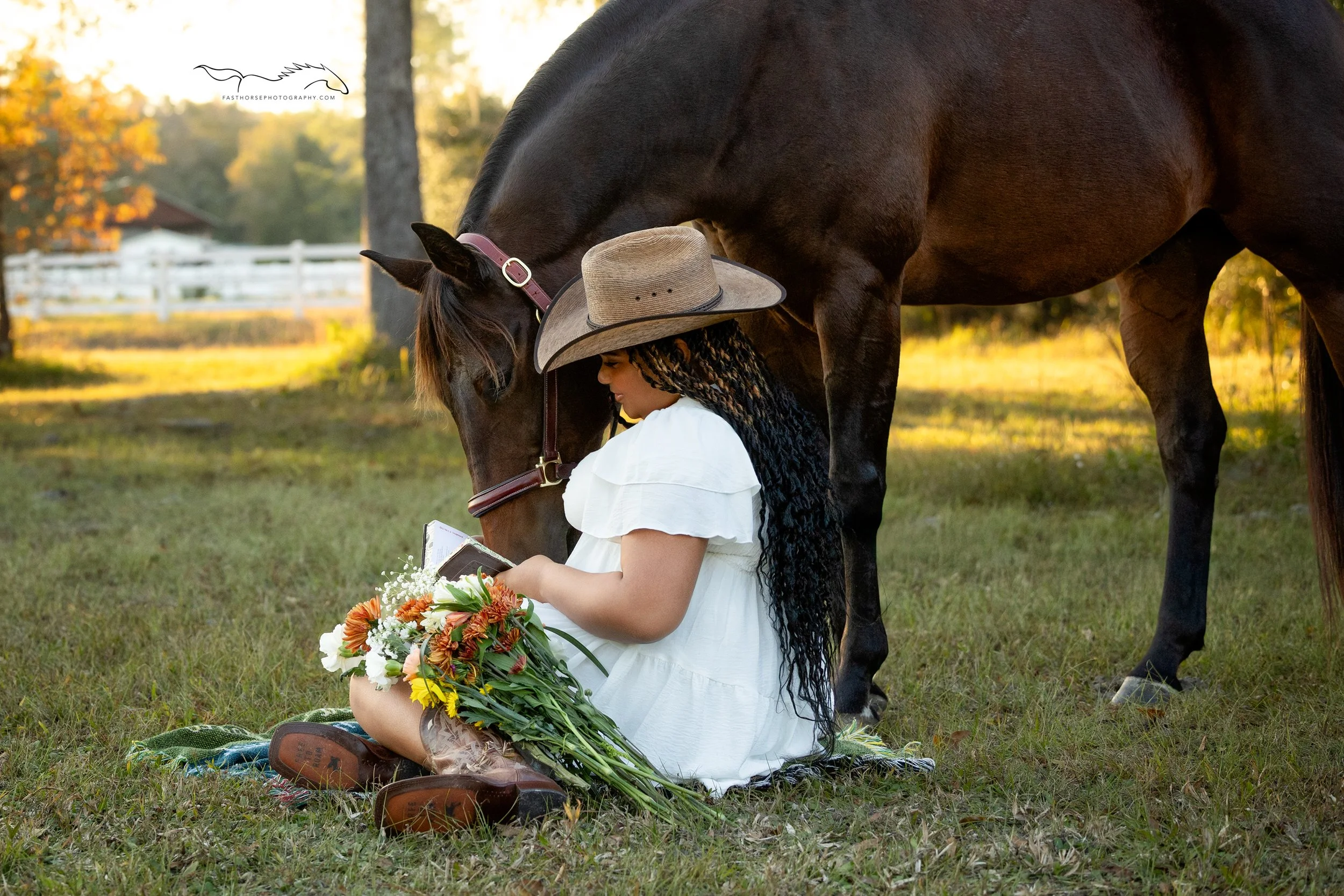 woman sits on the ground reading her bible while her horse looks over her shoulder