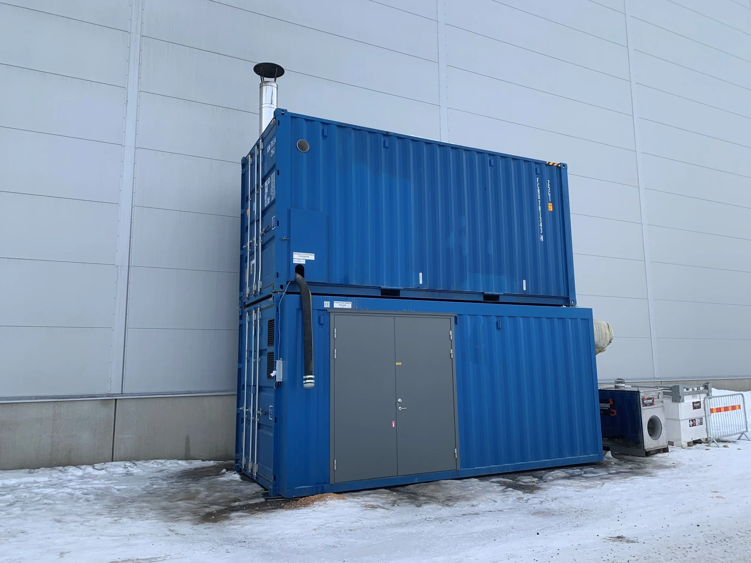 två sjöcontainers på varandra med byggvärme inuti står i snö