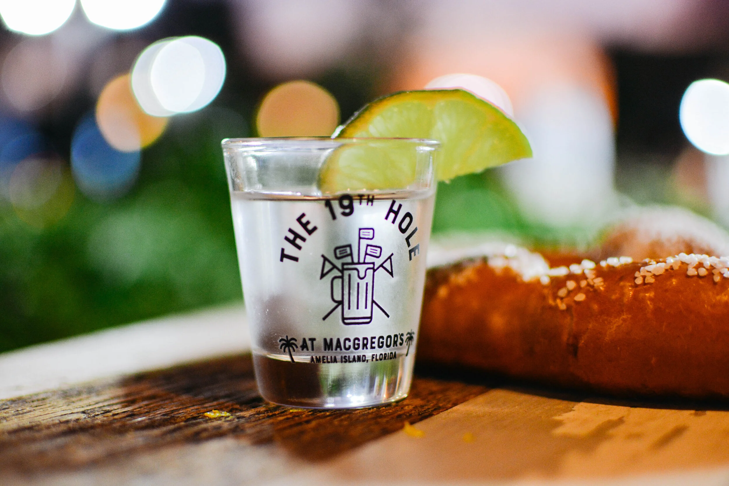 Shot glass with lemon and pretzel behind