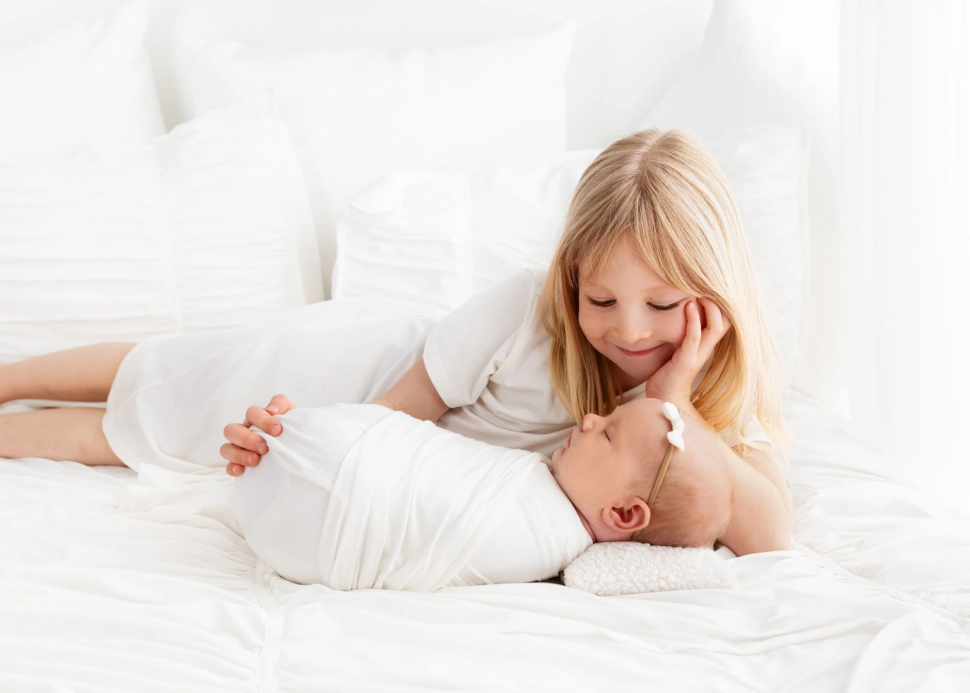 newborn-sister-bed-cuddle-white-victoria